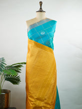 Gadwal Silk This elegant Gadwal saree is crafted from 100% pure silk in a rich blue with a mustard contrast.br
It features box check buttas with gold and silver motifs on the body and no border, offering a modern yet traditional appeal. Hanumatodi - Gadwal saree - Manoranjitham Weaves - Handloom Store