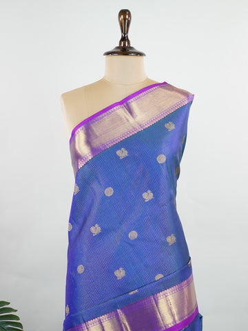 Kanchipuram Silk In a striking combination of blue and purple, this Vairavoosi Kanchipuram saree in 100% pure silk is woven with pure zari and finished with a medium border. Bold yet elegant, this drape mirrors the rhythm of traditional craft. A regal weave for those who carry confidence in colour. #Manoranjitham #VairavoosiWeave #KanjivaramSilks #HandloomStory #BoldAndTraditional Sreemaata - Pure Kanjivaram Silk Saree | Vairavoosi Weave - Manoranjitham Weaves - Handloom Store