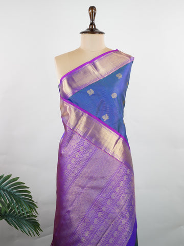 Kanchipuram Silk In a striking combination of blue and purple, this Vairavoosi Kanchipuram saree in 100% pure silk is woven with pure zari and finished with a medium border. Bold yet elegant, this drape mirrors the rhythm of traditional craft. A regal weave for those who carry confidence in colour. #Manoranjitham #VairavoosiWeave #KanjivaramSilks #HandloomStory #BoldAndTraditional Sreemaata - Pure Kanjivaram Silk Saree | Vairavoosi Weave - Manoranjitham Weaves - Handloom Store