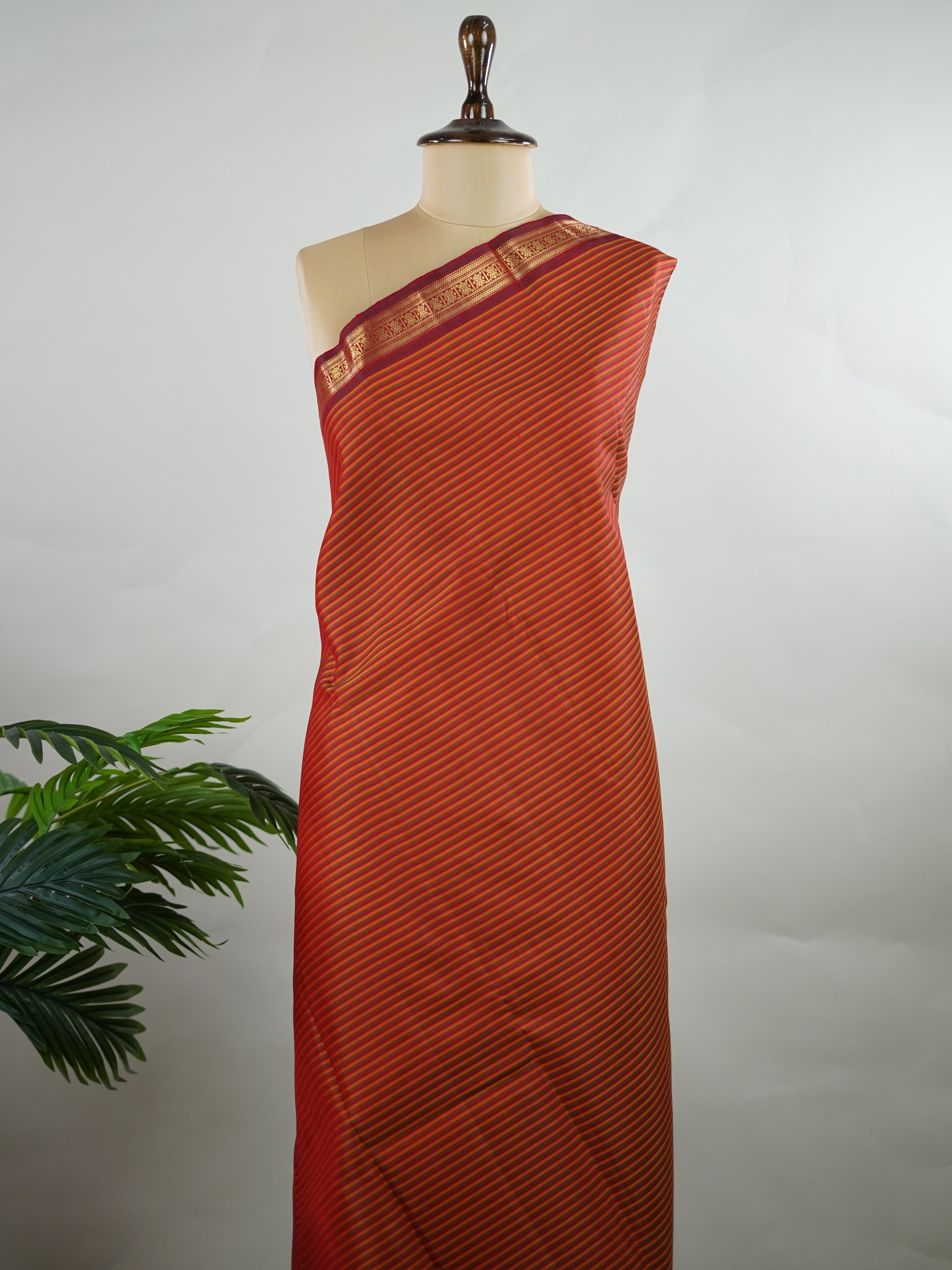 Kanchipuram Silk Multicolour handloom Kanjivaram with vibrant orange, green and maroon stripes, exuding vintage charm.
Paired with a delicate maroon border, this saree brings timeless elegance and a refined festive look. Kamakshi - Manoranjitham Weaves - Handloom Store