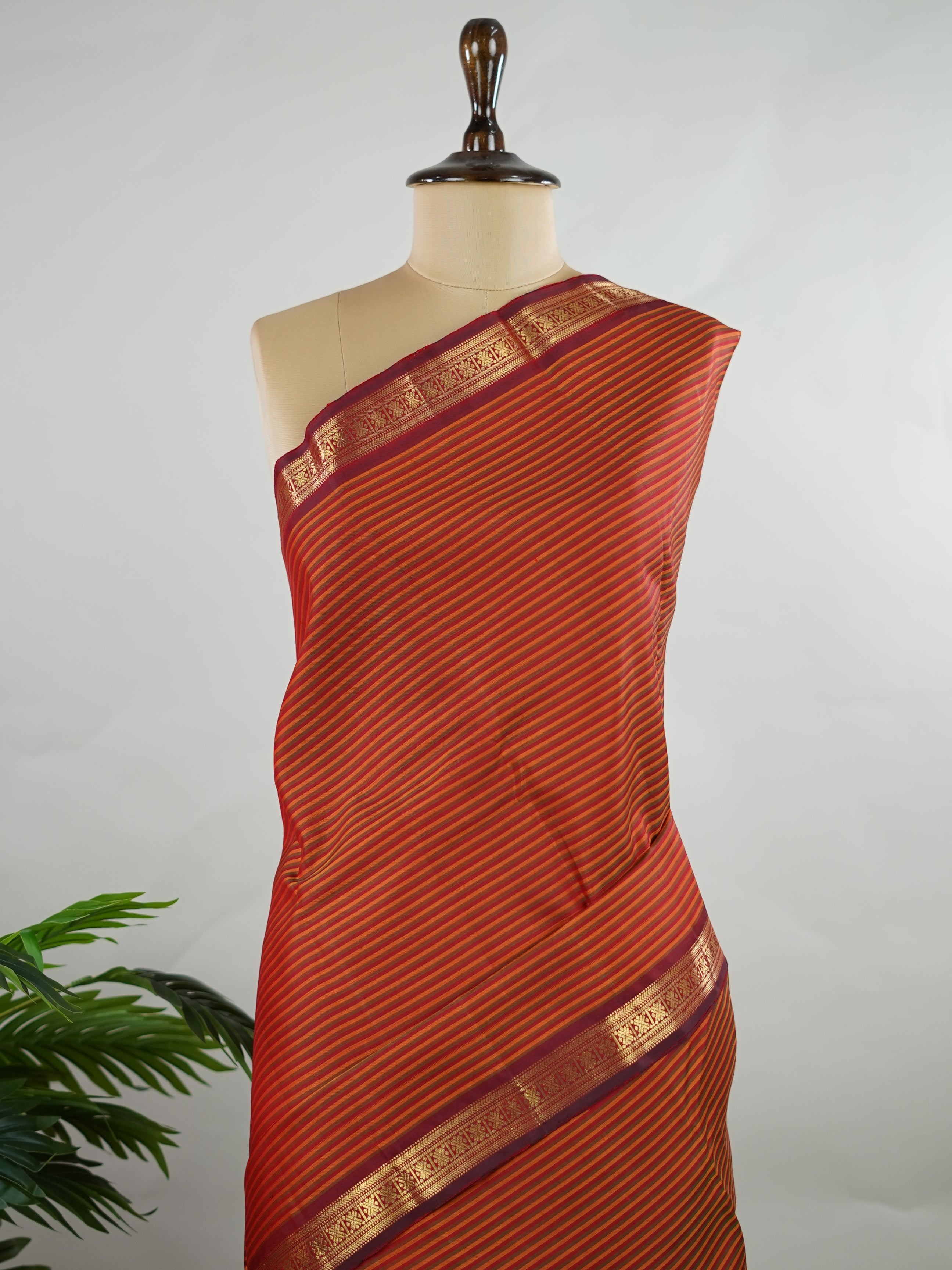 Kanchipuram Silk Multicolour handloom Kanjivaram with vibrant orange, green and maroon stripes, exuding vintage charm.
Paired with a delicate maroon border, this saree brings timeless elegance and a refined festive look. Kamakshi - Manoranjitham Weaves - Handloom Store