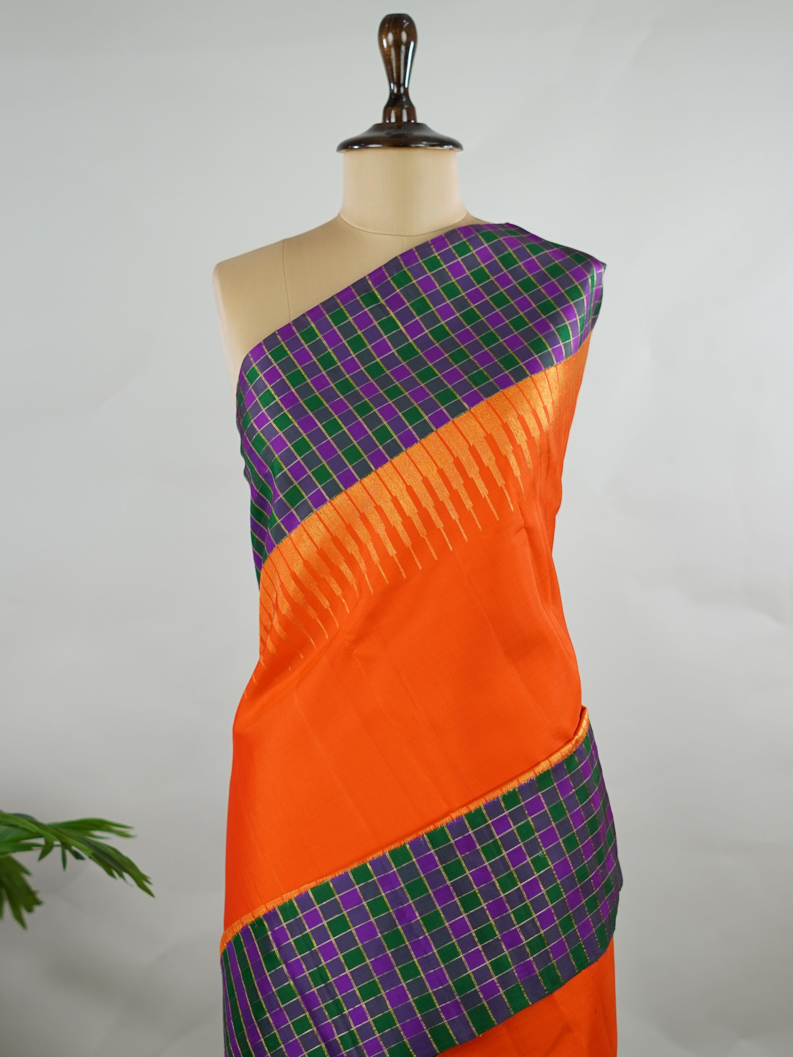 Kanchipuram Silk Pure silk in vibrant orange.
Paired with temple borders and multi-colour checked borders.
Blouse and pallu echo the same border design for a harmonious, elegant look. Kamini - Manoranjitham Weaves - Handloom Store
