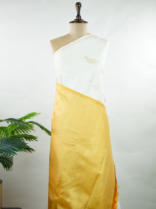 Kanchipuram Silk Elegant and refreshing, this white and yellow Kanjivaram saree is woven in luxurious 100% pure silk for a rich, graceful drape. The body features charming parrot motifs that stand out beautifully against the soft contrast tones. Designed without a traditional border, it offers a modern, seamless look while retaining the timeless grandeur of classic Kanjivaram craftsmanship. Tripurasundari - Manoranjitham Weaves - Handloom Store