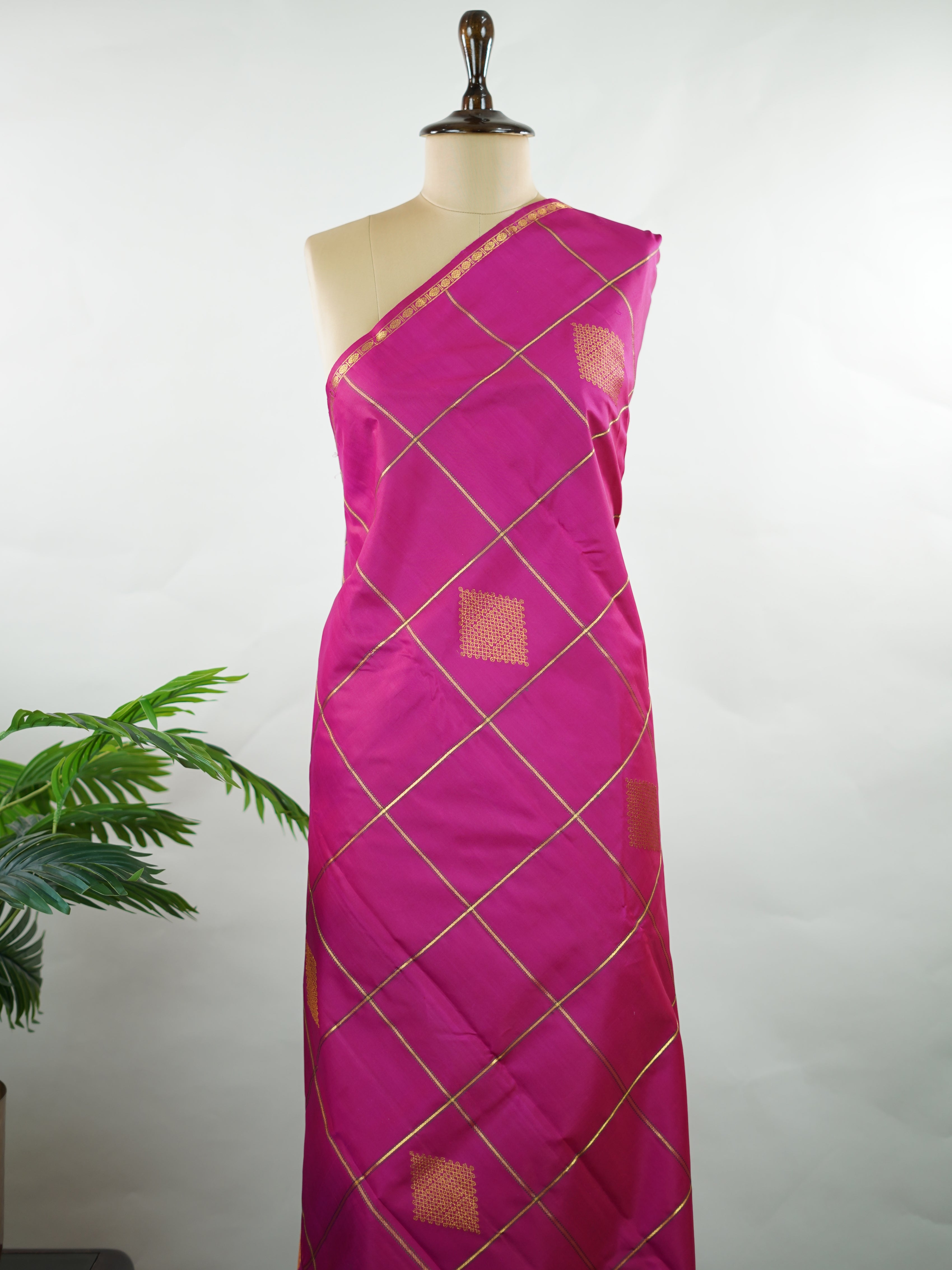 Kanchipuram Silk A beautiful celebration of tradition, this pink and green Kanjivaram saree is woven in rich 100% pure silk for a regal drape. The body features intricate Kolam buttis paired with classic checks, creating a harmonious blend of heritage artistry and structured design. Vibrant yet timeless, it’s a perfect choice for weddings, festive gatherings, and special occasions. Shambhavi - Green Pure Kanjivaram Silk Saree - Manoranjitham Weaves - Handloom Store