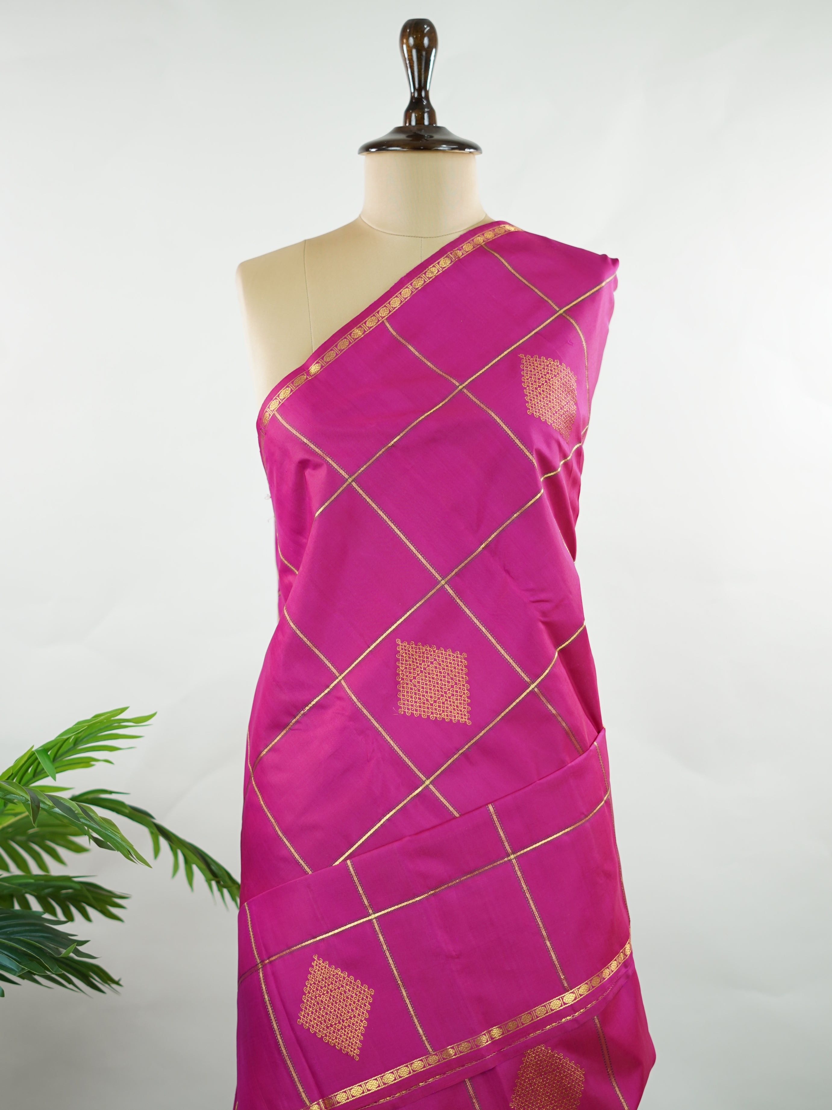 Kanchipuram Silk A beautiful celebration of tradition, this pink and green Kanjivaram saree is woven in rich 100% pure silk for a regal drape. The body features intricate Kolam buttis paired with classic checks, creating a harmonious blend of heritage artistry and structured design. Vibrant yet timeless, it’s a perfect choice for weddings, festive gatherings, and special occasions. Shambhavi - Green Pure Kanjivaram Silk Saree - Manoranjitham Weaves - Handloom Store