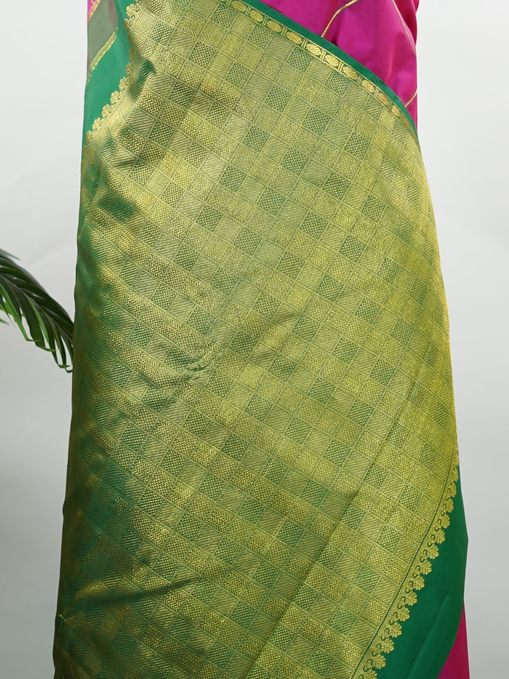 Kanchipuram Silk A beautiful celebration of tradition, this pink and green Kanjivaram saree is woven in rich 100% pure silk for a regal drape. The body features intricate Kolam buttis paired with classic checks, creating a harmonious blend of heritage artistry and structured design. Vibrant yet timeless, it’s a perfect choice for weddings, festive gatherings, and special occasions. Shambhavi - Green Pure Kanjivaram Silk Saree - Manoranjitham Weaves - Handloom Store