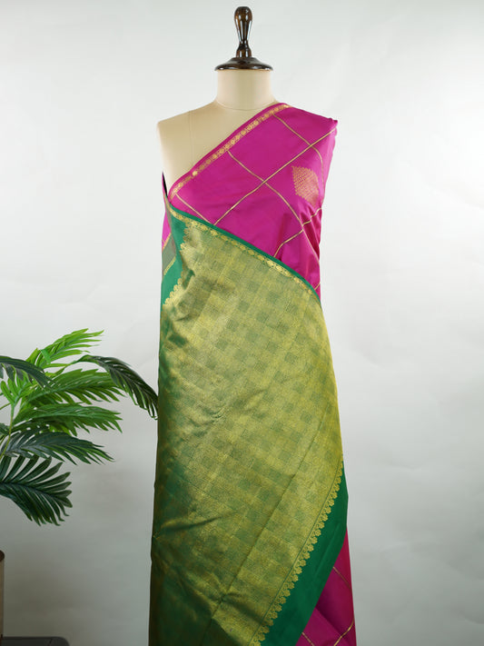 Kanchipuram Silk A beautiful celebration of tradition, this pink and green Kanjivaram saree is woven in rich 100% pure silk for a regal drape. The body features intricate Kolam buttis paired with classic checks, creating a harmonious blend of heritage artistry and structured design. Vibrant yet timeless, it’s a perfect choice for weddings, festive gatherings, and special occasions. Shambhavi - Manoranjitham Weaves - Handloom Store