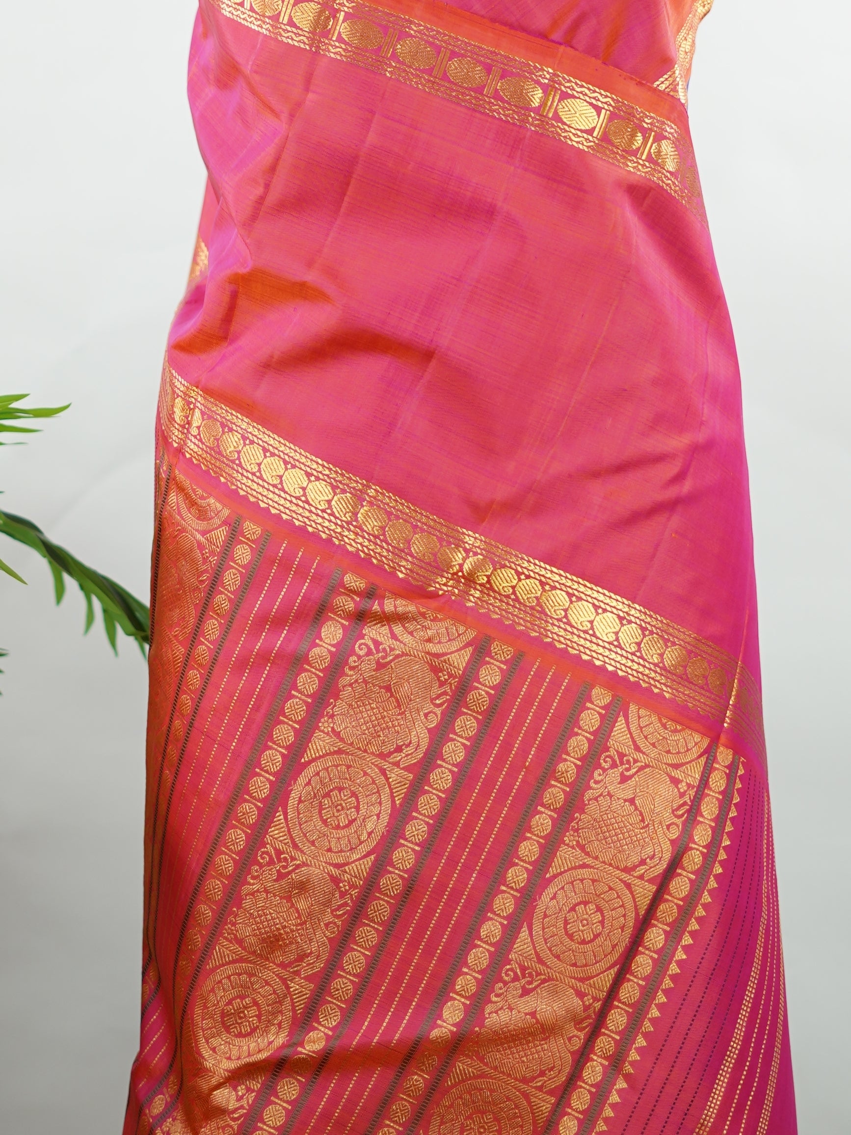 Kanchipuram Silk Elegant and striking, this violet Kanjivaram saree is woven in luxurious 100% pure silk for a rich, graceful drape. The body is adorned with delicate buttis, while the contrasting pinkish orange gap border adds a bold and contemporary touch. A perfect fusion of classic tradition and statement design—ideal for weddings and festive celebrations Mahamaya - Violet Pure Kanjivaram Silk Saree - Manoranjitham Weaves - Handloom Store
