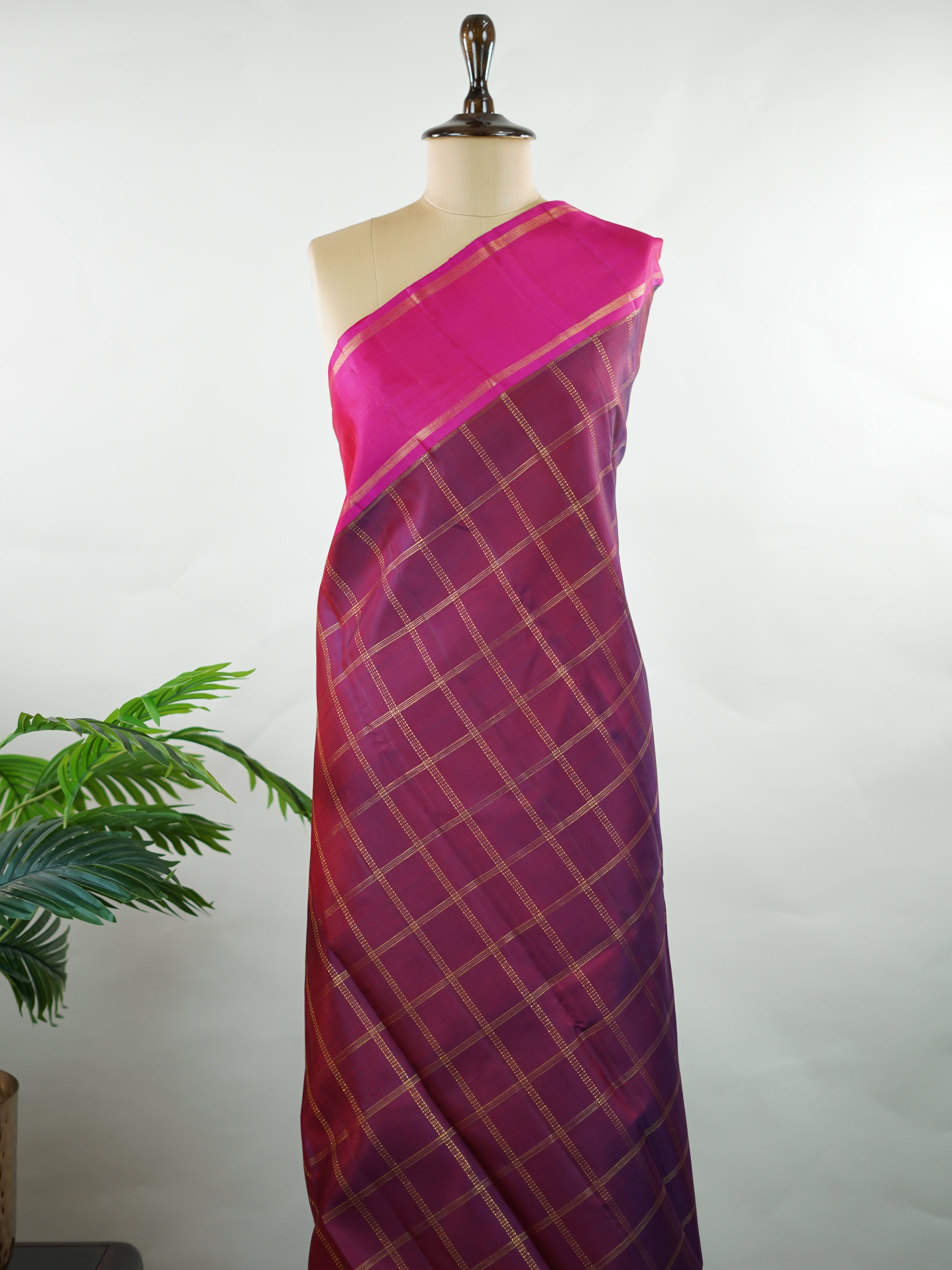 Kanchipuram Silk Rich and regal, this maroon Kanjivaram saree is crafted in luxurious 100% pure silk. The bold big checks create a striking traditional pattern, beautifully complemented by a contrasting pink gatti border. A grand and timeless choice for weddings and festive occasions. Shivaduti - Maroon Pure Kanjivaram Silk Saree | Classic Checks - Manoranjitham Weaves - Handloom Store