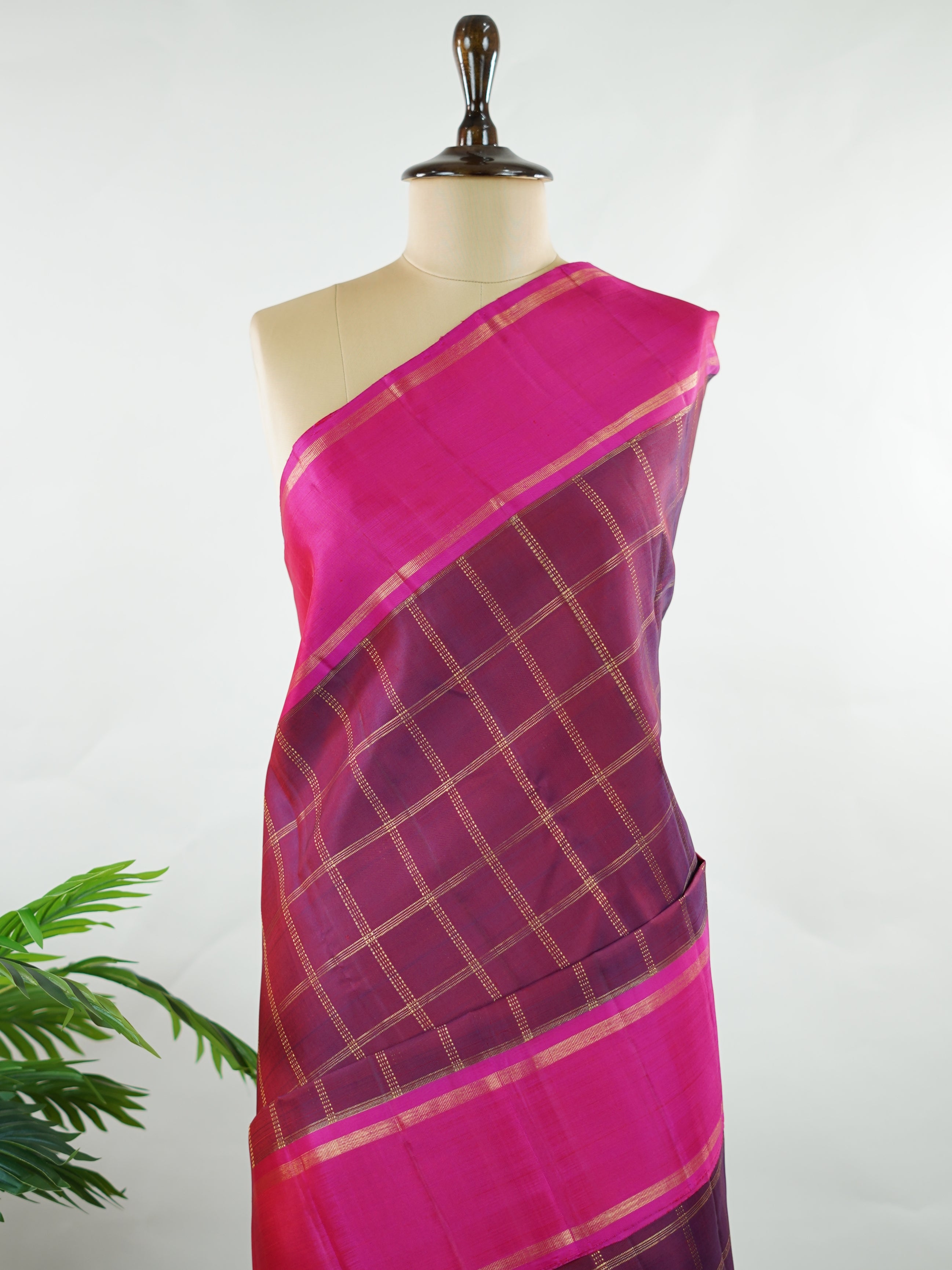 Kanchipuram Silk Rich and regal, this maroon Kanjivaram saree is crafted in luxurious 100% pure silk. The bold big checks create a striking traditional pattern, beautifully complemented by a contrasting pink gatti border. A grand and timeless choice for weddings and festive occasions. Shivaduti - Maroon Pure Kanjivaram Silk Saree | Classic Checks - Manoranjitham Weaves - Handloom Store