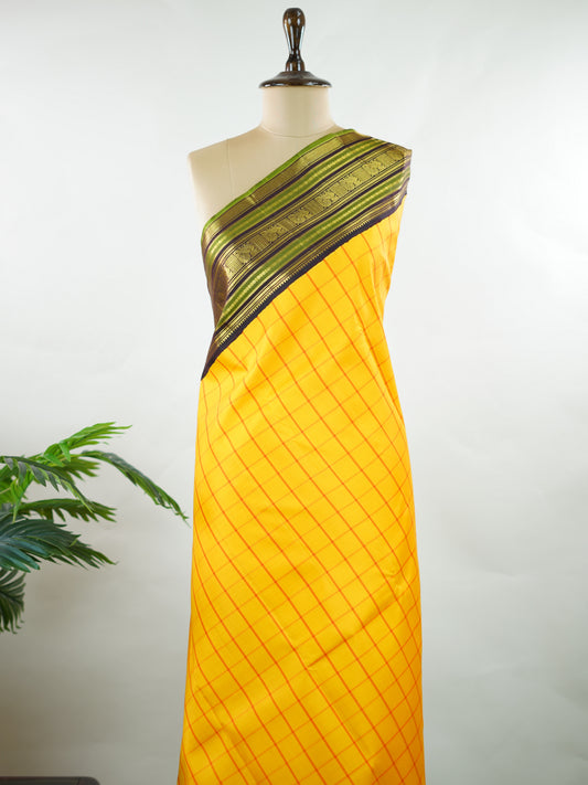 Kanchipuram Silk Bright and earthy in contrast, this yellow Kanjivaram saree features classic checks that enhance its traditional charm. The snuff-toned gatti border adds depth and definition, making it a vibrant yet elegant pick for celebrations and special gatherings Nityakalyani - Manoranjitham Weaves - Handloom Store