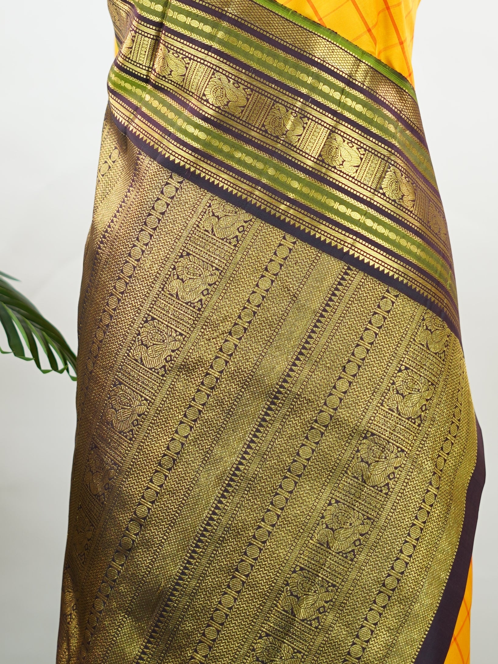 Kanchipuram Silk Bright and earthy in contrast, this yellow Kanjivaram saree features classic checks that enhance its traditional charm. The snuff-toned gatti border adds depth and definition, making it a vibrant yet elegant pick for celebrations and special gatherings Nityakalyani - Manoranjitham Weaves - Handloom Store