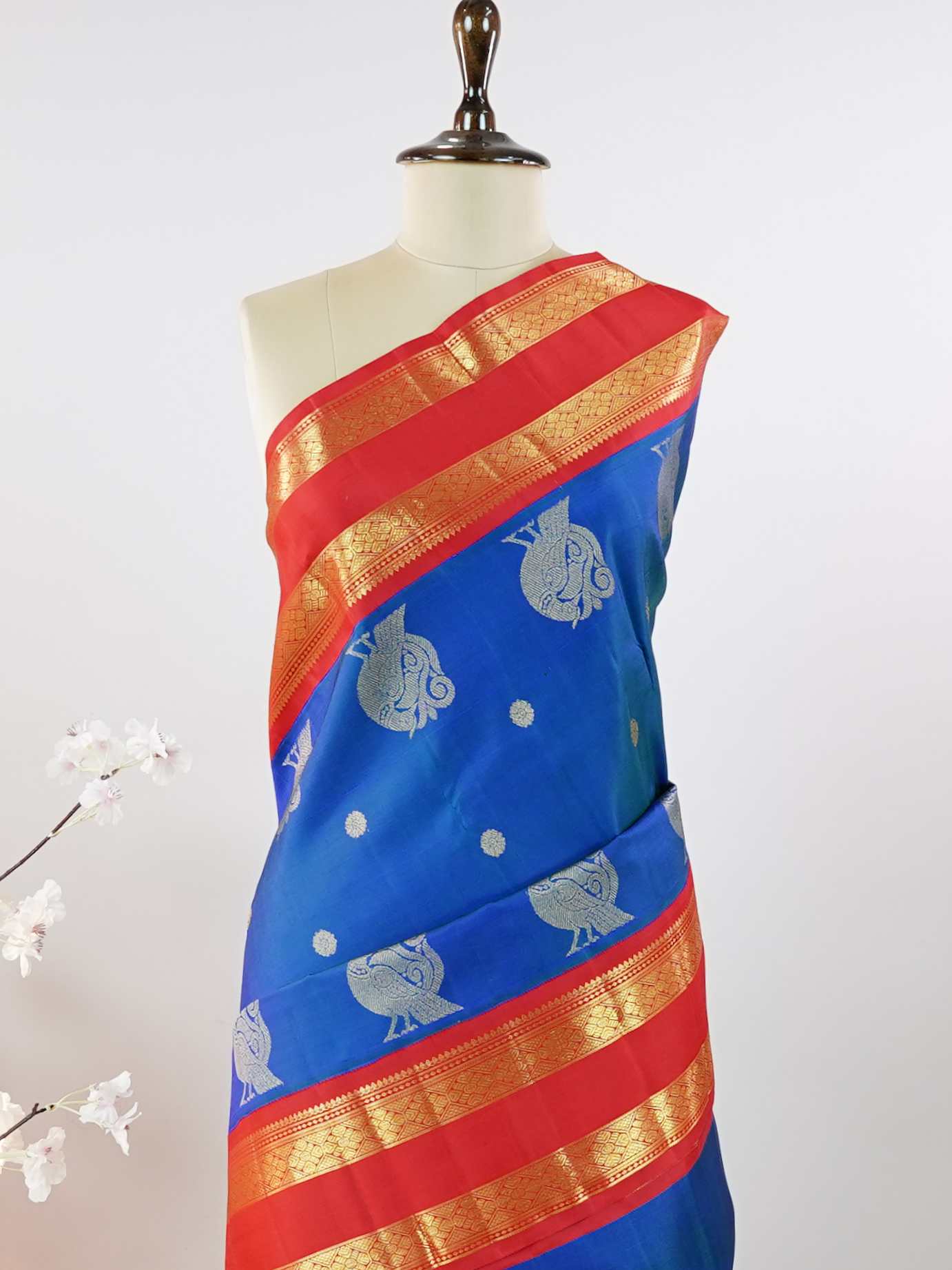 Kanchipuram Silk This exquisite Kanjivaram saree features a blue body with a striking red border, crafted from 100% pure silk.br
The body showcases a Korvai/Kuttu pattern, adorned with delicate flower motifs and peacocks flanking the border.br
Finished with elegant detailing, it beautifully highlights traditional handloom craftsmanship and timeless Kanchipuram artistry. Shivashakti - Blue Pure Kanjivaram Silk Saree - Manoranjitham Weaves - Handloom Store
