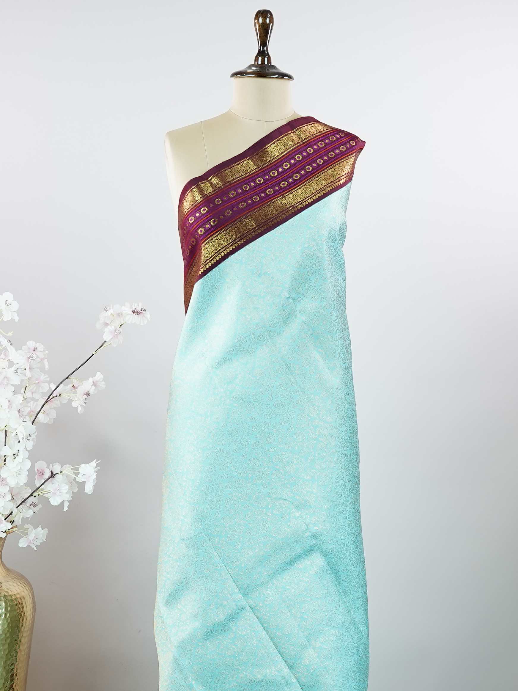 Kanchipuram Silk This elegant Kanjivaram saree features an aqua blue body with a rich maroon border, crafted from 100% pure silk. Handloom woven with full brocade and intricate meena work on the border and pallu, it reflects the timeless artistry of Kanchipuram. Chintamani - Aqua Blue Pure Kanjivaram Silk Saree - Manoranjitham Weaves - Handloom Store