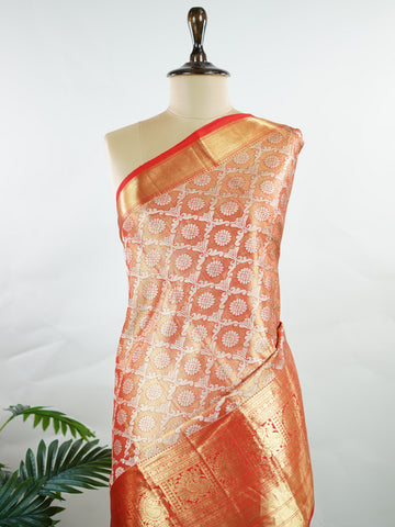 Kanchipuram Silk This Kanjivaram silk saree, adorned in Coral  and detailed with Pure Zari weaving, reflects the grandeur of Kanchipuram. The timeless Buttis motifs enhance its bridal charm. A perfect blend of luxury and tradition, it is designed for those who appreciate fine craftsmanship. Kalyani - Manoranjitham Weaves - Handloom Store