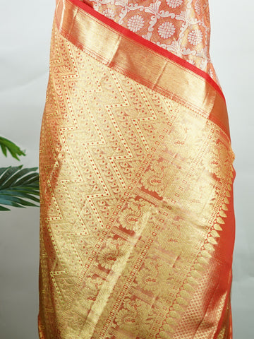 Kanchipuram Silk This Kanjivaram silk saree, adorned in Coral  and detailed with Pure Zari weaving, reflects the grandeur of Kanchipuram. The timeless Buttis motifs enhance its bridal charm. A perfect blend of luxury and tradition, it is designed for those who appreciate fine craftsmanship. Kalyani - Manoranjitham Weaves - Handloom Store