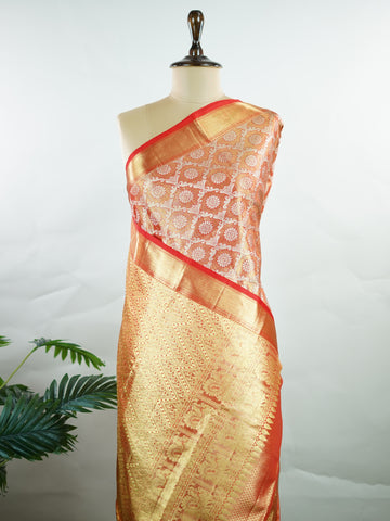 Kanchipuram Silk This Kanjivaram silk saree, adorned in Coral  and detailed with Pure Zari weaving, reflects the grandeur of Kanchipuram. The timeless Buttis motifs enhance its bridal charm. A perfect blend of luxury and tradition, it is designed for those who appreciate fine craftsmanship. Kalyani - Manoranjitham Weaves - Handloom Store