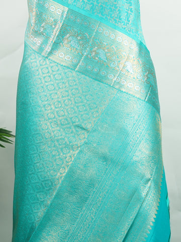 Kanchipuram Silk A pure Kanchipuram silk in tranquil cyan, adorned with gold and silver zari buttas. The self-border enhances the saree's seamless elegance, making it an exquisite choice for celebrations. Woven with precision, this handloom drape is a timeless ode to tradition.    #ManoranjithamSilks #KanjivaramHandloom #PureSilkSaree #BridalElegance #TimelessTradition Charukesi - Pure Kanjivaram Silk Saree | Zari Buttas - Manoranjitham Weaves - Handloom Store
