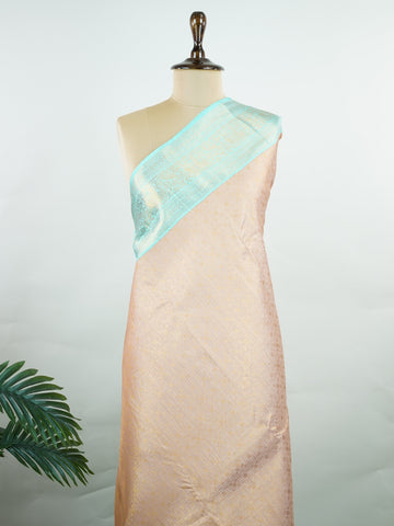 Kanchipuram Silk A delicate peach Kanchipuram silk saree woven with gold zari buttas, reflecting quiet sophistication. The cyan border adds a refreshing vibrance, creating a unique interplay of colours. Crafted from 100% pure silk, this saree is a testament to timeless handloom artistry. Perfect for bridal trousseaus and festive celebrations.          #ManoranjithamSilks #KanjivaramHandloom #PureSilkSaree #BridalElegance #TimelessTradition Surutia - Pure Kanjivaram Silk Saree | Zari Buttas - Manoranjitham W