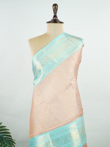 Kanchipuram Silk A delicate peach Kanchipuram silk saree woven with gold zari buttas, reflecting quiet sophistication. The cyan border adds a refreshing vibrance, creating a unique interplay of colours. Crafted from 100% pure silk, this saree is a testament to timeless handloom artistry. Perfect for bridal trousseaus and festive celebrations.          #ManoranjithamSilks #KanjivaramHandloom #PureSilkSaree #BridalElegance #TimelessTradition Surutia - Pure Kanjivaram Silk Saree | Zari Buttas - Manoranjitham W