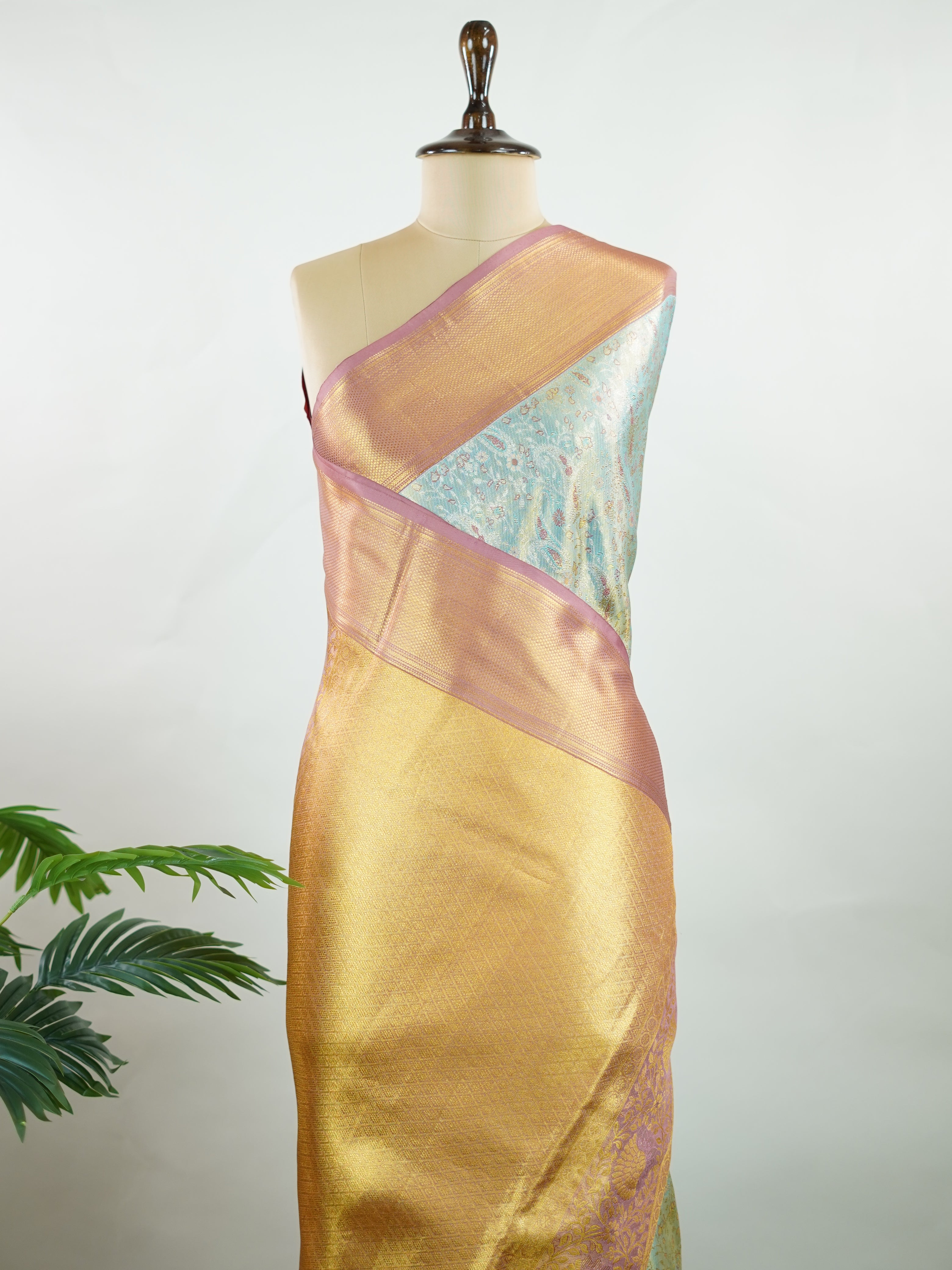 Kanchipuram Silk Earthy olive green silk paired with red borders, woven with gold and silver zari buttas that glimmer softly. This saree blends tradition with understated elegance. Made from 100% pure silk, it speaks of timeless beauty. A perfect drape for weddings and special occasions.            #ManoranjithamSilks #KanjivaramHandloom #PureSilkSaree #BridalElegance #TimelessTradition Gowrimanohari - Green Pure Kanjivaram Silk Saree | Zari Buttas - Manoranjitham Weaves - Handloom Store
