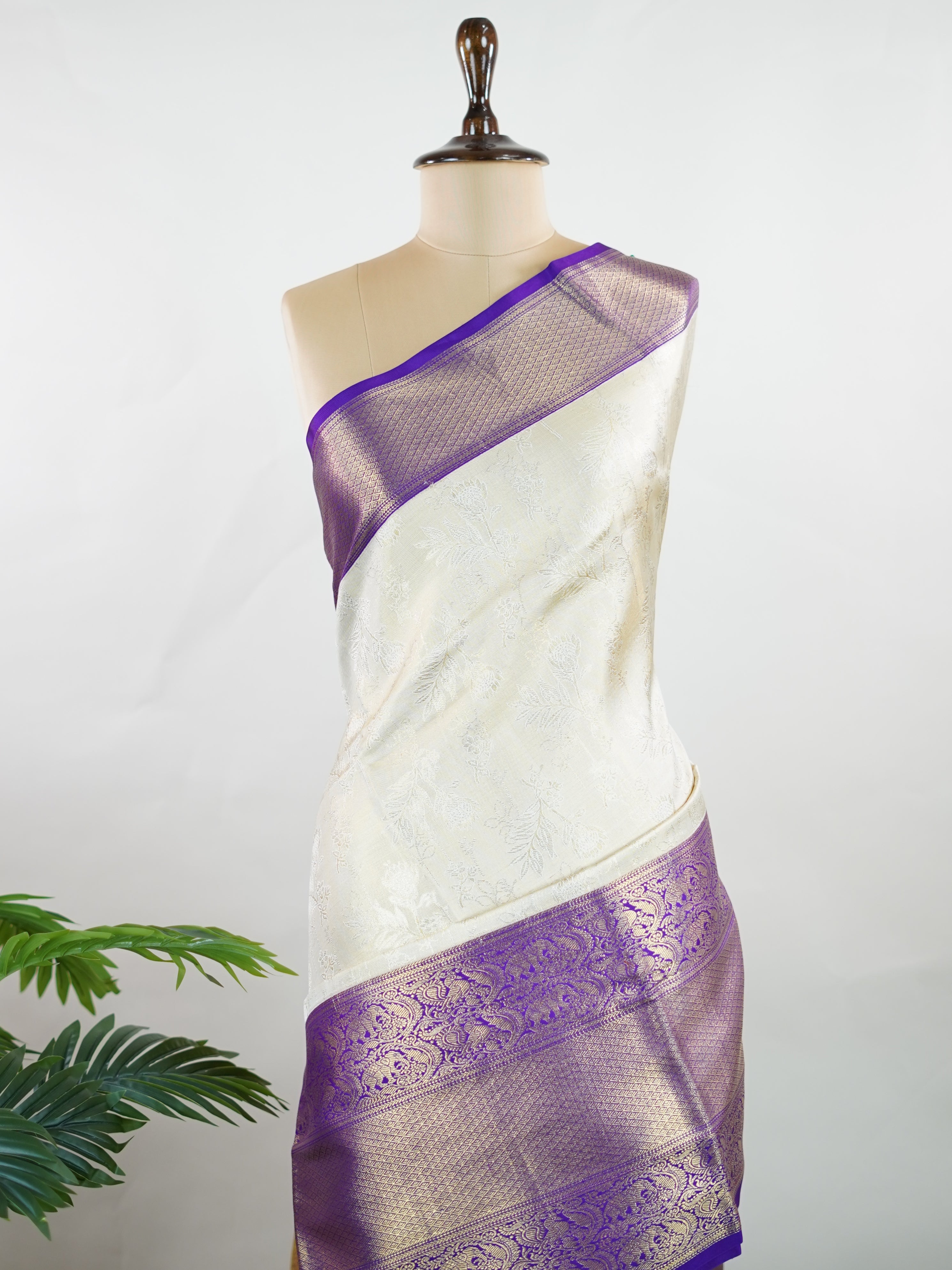 Kanchipuram Silk A classic cream silk saree with purple borders, adorned with delicate zari buttis scattered across the weave. The rich contrast blends tradition with grace. Woven in Kanchipuram from 100% pure silk, it's perfect for weddings and festive occasions. A timeless drape for treasured moments.                     #ManoranjithamSilks #KanjivaramHandloom #PureSilkSaree #BridalElegance #TimelessTradition Vagadeeshwari - Cream Pure Kanjivaram Silk Saree | Zari Buttas - Manoranjitham Weaves - Handloom 