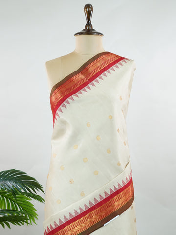 Gadwal Silk This elegant Gadwal saree features a beige body paired with a red border, crafted from 100% pure silk.br
The body is adorned with delicate gold mango and rudraksha buttis, adding a touch of traditional charm.br
Finished with a subtle small border, it showcases the exquisite handloom artistry of Gadwal weaving. Mangala - Beige Handloom Gadwal Silk Saree | Pure Silk | Zari Border - Manoranjitham Weaves - Handloom Store
