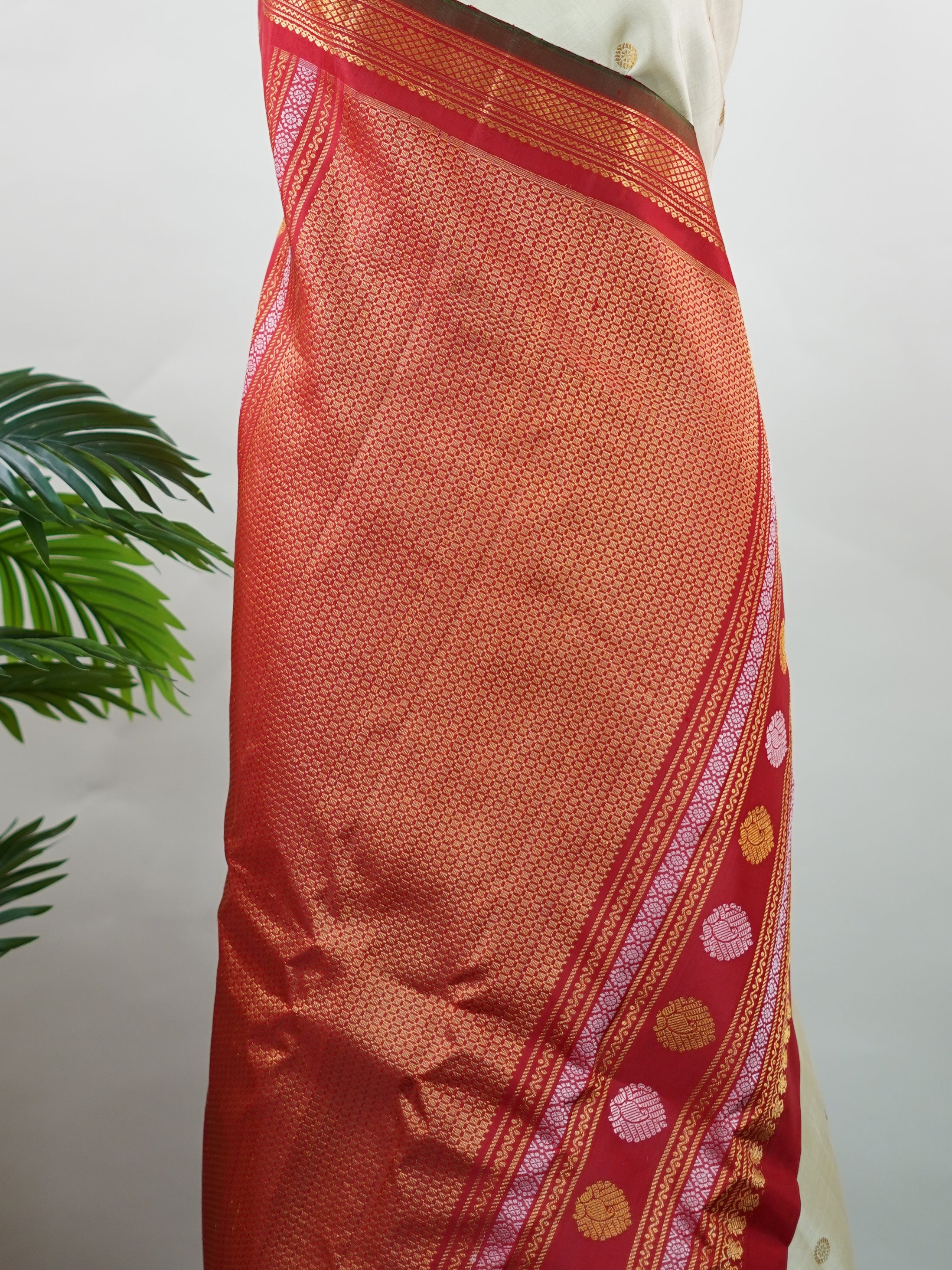 Gadwal Silk This elegant Gadwal saree features a beige body paired with a red border, crafted from 100% pure silk.br
The body is adorned with delicate gold mango and rudraksha buttis, adding a touch of traditional charm.br
Finished with a subtle small border, it showcases the exquisite handloom artistry of Gadwal weaving. Mangala - Beige Handloom Gadwal Silk Saree | Pure Silk | Zari Border - Manoranjitham Weaves - Handloom Store