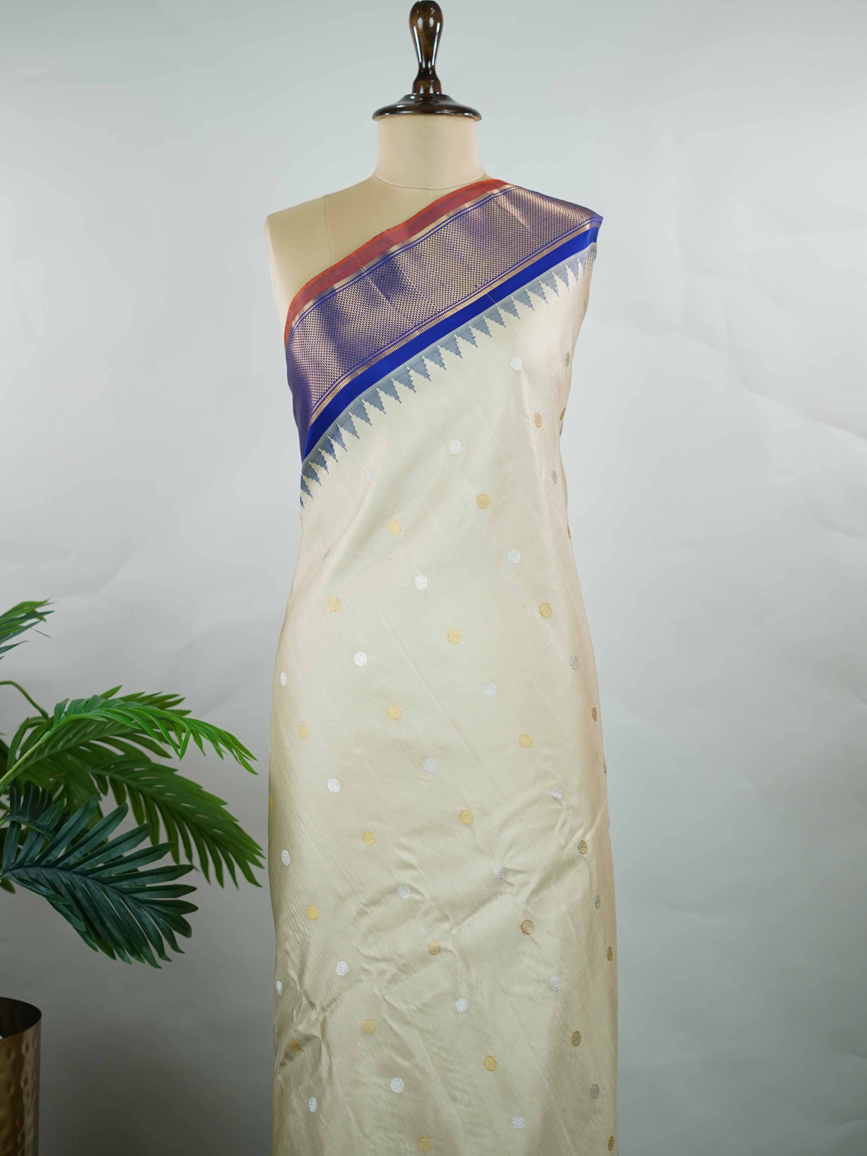 Gadwal Silk Elevate your ethnic elegance with this Gadwal saree in a graceful beige shade, paired with a royal blue blouse. The saree is beautifully adorned with gold and silver buttas that add a subtle festive shimmer. Its traditional weave ensures a rich drape that blends sophistication with cultural charm. Perfect for weddings, festive occasions, and celebrations that call for timeless beauty. Shivaatmika - Handloom Gadwal Silk Saree | Pure Silk | Zari Border - Manoranjitham Weaves - Handloom Store