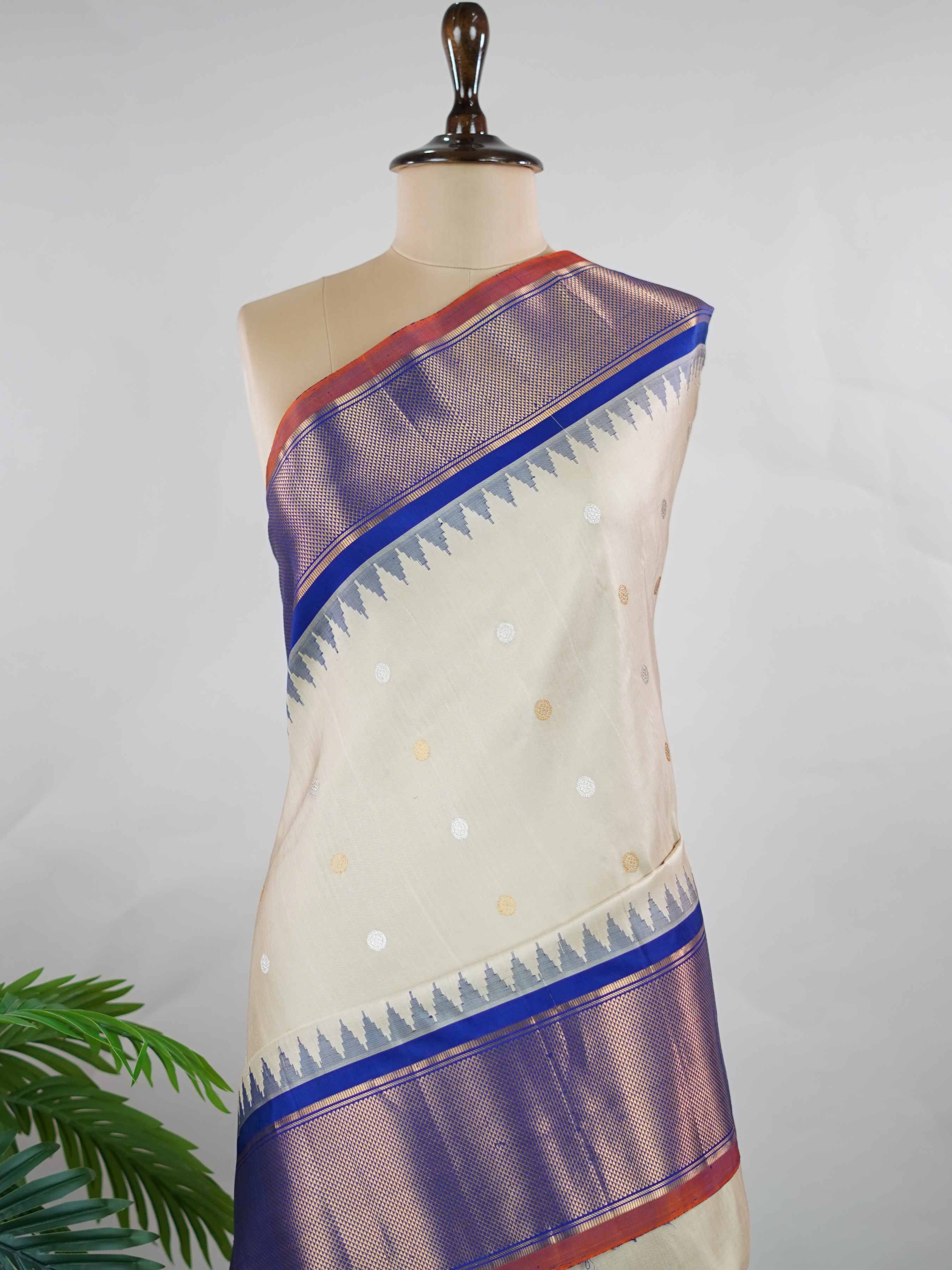 Gadwal Silk Elevate your ethnic elegance with this Gadwal saree in a graceful beige shade, paired with a royal blue blouse. The saree is beautifully adorned with gold and silver buttas that add a subtle festive shimmer. Its traditional weave ensures a rich drape that blends sophistication with cultural charm. Perfect for weddings, festive occasions, and celebrations that call for timeless beauty. Shivaatmika - Handloom Gadwal Silk Saree | Pure Silk | Zari Border - Manoranjitham Weaves - Handloom Store