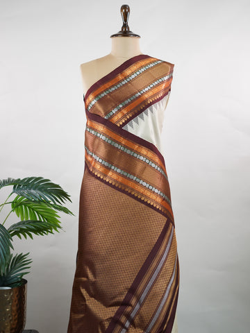 Gadwal Silk This elegant Gadwal saree features a beige body paired with a rich brown border, crafted from 100% pure silk.br
The body is adorned with subtle zari buttis, adding delicate shimmer and charm.br
Finished with a bold, wide border, it showcases the classic handloom artistry of Gadwal weaving. Parvathipriya - Gadwal  saree - Manoranjitham Weaves - Handloom Store