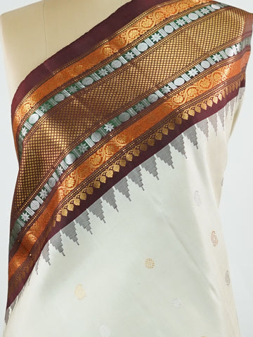 Gadwal Silk This elegant Gadwal saree features a beige body paired with a rich brown border, crafted from 100% pure silk.br
The body is adorned with subtle zari buttis, adding delicate shimmer and charm.br
Finished with a bold, wide border, it showcases the classic handloom artistry of Gadwal weaving. Parvathipriya - Gadwal  saree - Manoranjitham Weaves - Handloom Store