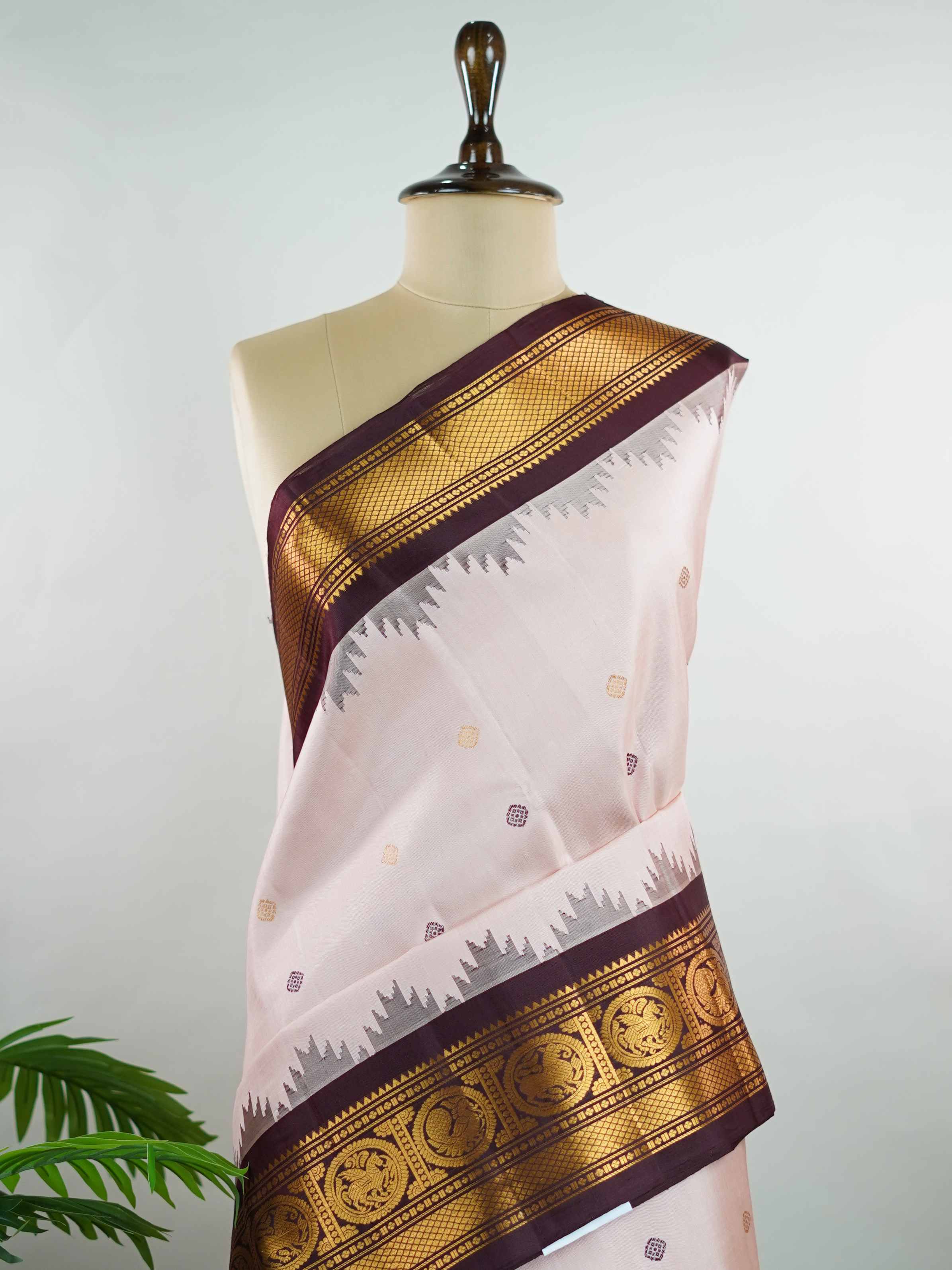 Gadwal Silk Make a graceful statement with this Gadwal saree in a rich peach shade, paired with a deep brown blouse. The design is enhanced with elegant gold and silk buttas, reflecting traditional craftsmanship and subtle luxury. Its classic weave ensures a refined drape that beautifully blends comfort with sophistication. Perfect for festive occasions, cultural events, and celebrations that call for timeless ethnic elegance. Indumati - Handloom Gadwal Silk Saree | Pure Silk | Zari Border - Manoranjitham W