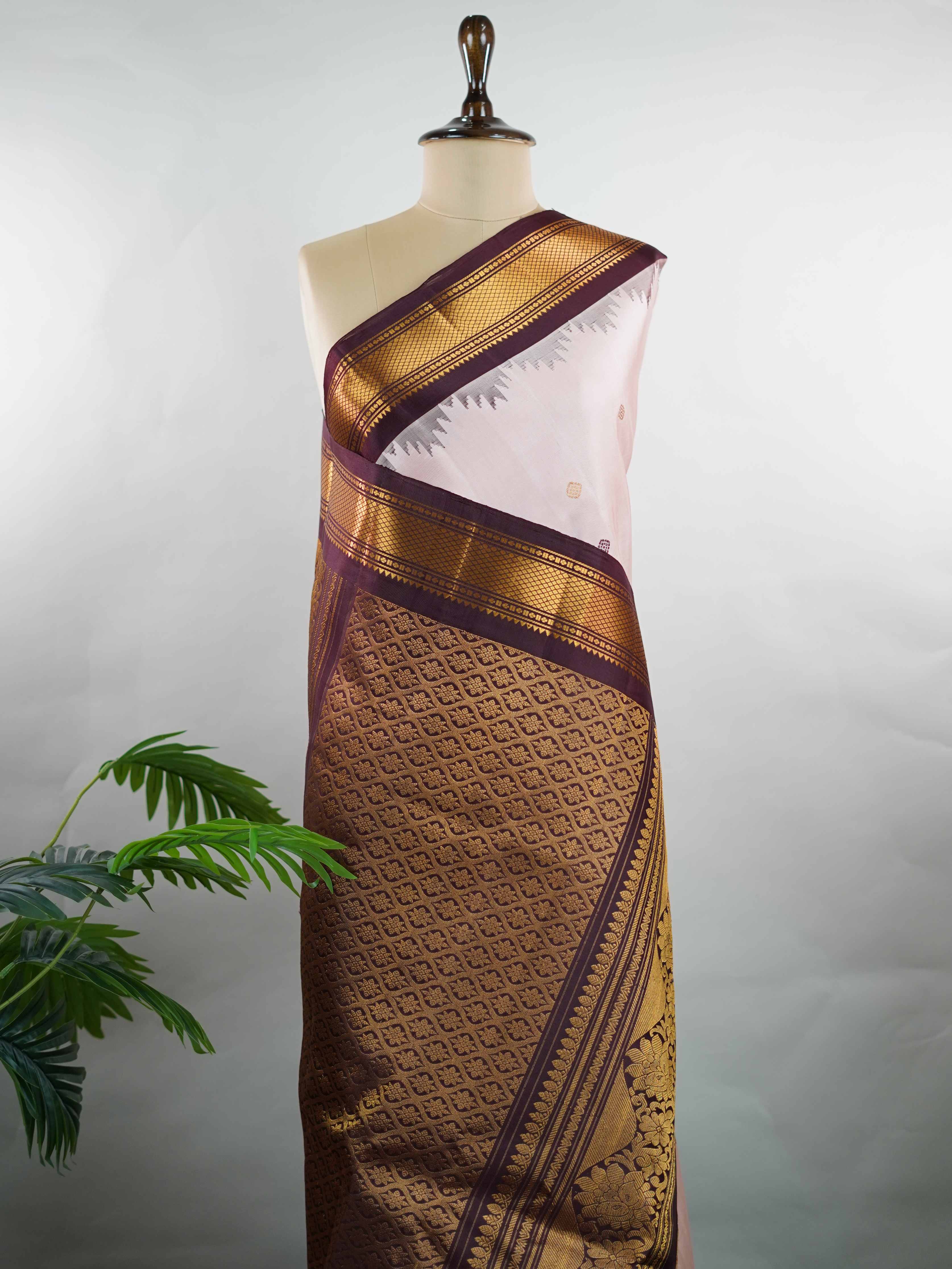 Gadwal Silk Make a graceful statement with this Gadwal saree in a rich peach shade, paired with a deep brown blouse. The design is enhanced with elegant gold and silk buttas, reflecting traditional craftsmanship and subtle luxury. Its classic weave ensures a refined drape that beautifully blends comfort with sophistication. Perfect for festive occasions, cultural events, and celebrations that call for timeless ethnic elegance. Indumati - Handloom Gadwal Silk Saree | Pure Silk | Zari Border - Manoranjitham W