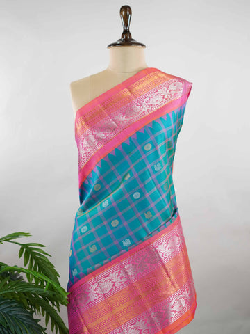 Gadwal Silk Stand out in elegance with this Gadwal saree in a rich peacock blue shade, paired beautifully with a contrasting pink blouse. The weave is adorned with silver and gold Chakram and Annapakshi buttas, showcasing exquisite traditional artistry. The fine detailing adds a regal charm, making it a perfect blend of heritage and sophistication.  Satyavati - Handloom Gadwal Silk Saree | Pure Silk | Zari Border - Manoranjitham Weaves - Handloom Store