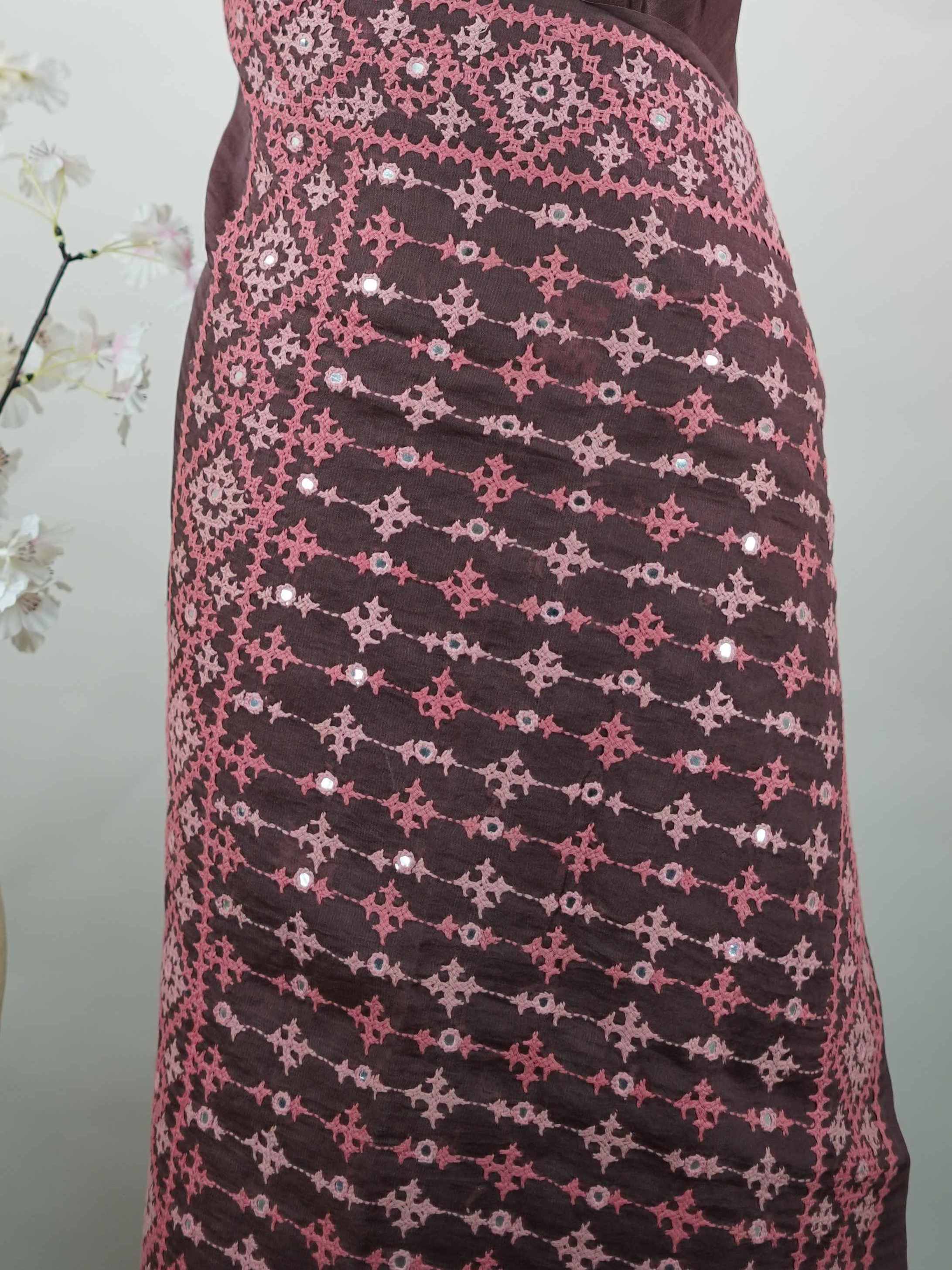 Katan A warm brown Kora saree highlighted with soft pink accents, creating a graceful contrast.br
Enhanced with vibrant Kutch embroidery, it showcases rich artisanal detail with a refined, contemporary appeal. Kadhambari - Warm Brown Kora Silk Saree | Kutch Work - Manoranjitham Weaves - Handloom Store