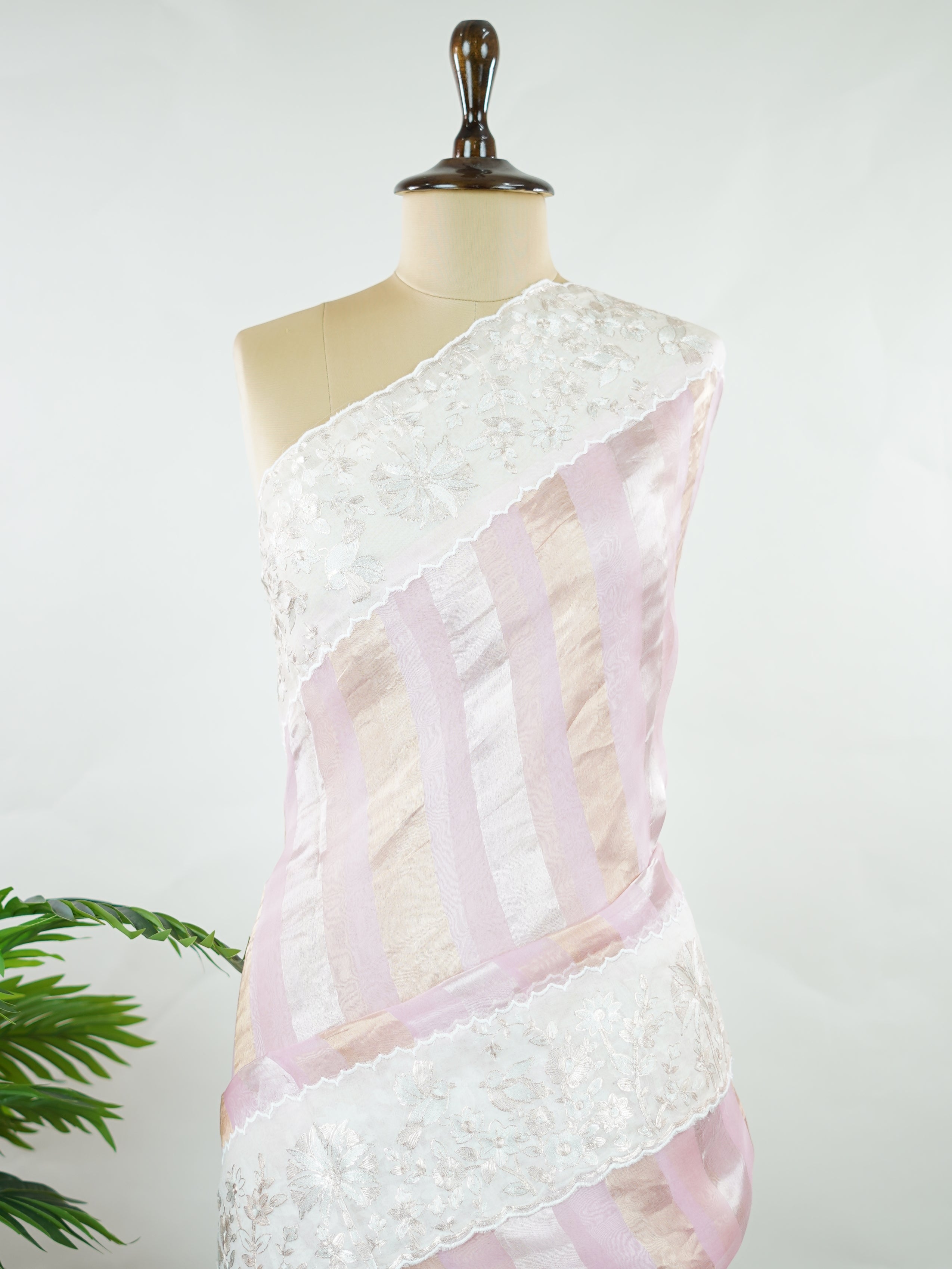 Organza Elegant organza saree in pink and white tones featuring delicate Aari Peeta work on the pallu. The sheer, lightweight fabric drapes softly, giving a graceful and feminine silhouette.br data-start=184 data-end=187Intricate handcrafted embroidery enhances its charm with rich detail and subtle elegance.br data-start=276 data-end=279Perfect for weddings, festive celebrations, and special occasions with timeless ethnic beauty. Aira - Organza Saree | Embroidered - Manoranjitham Weaves - Handloom Store