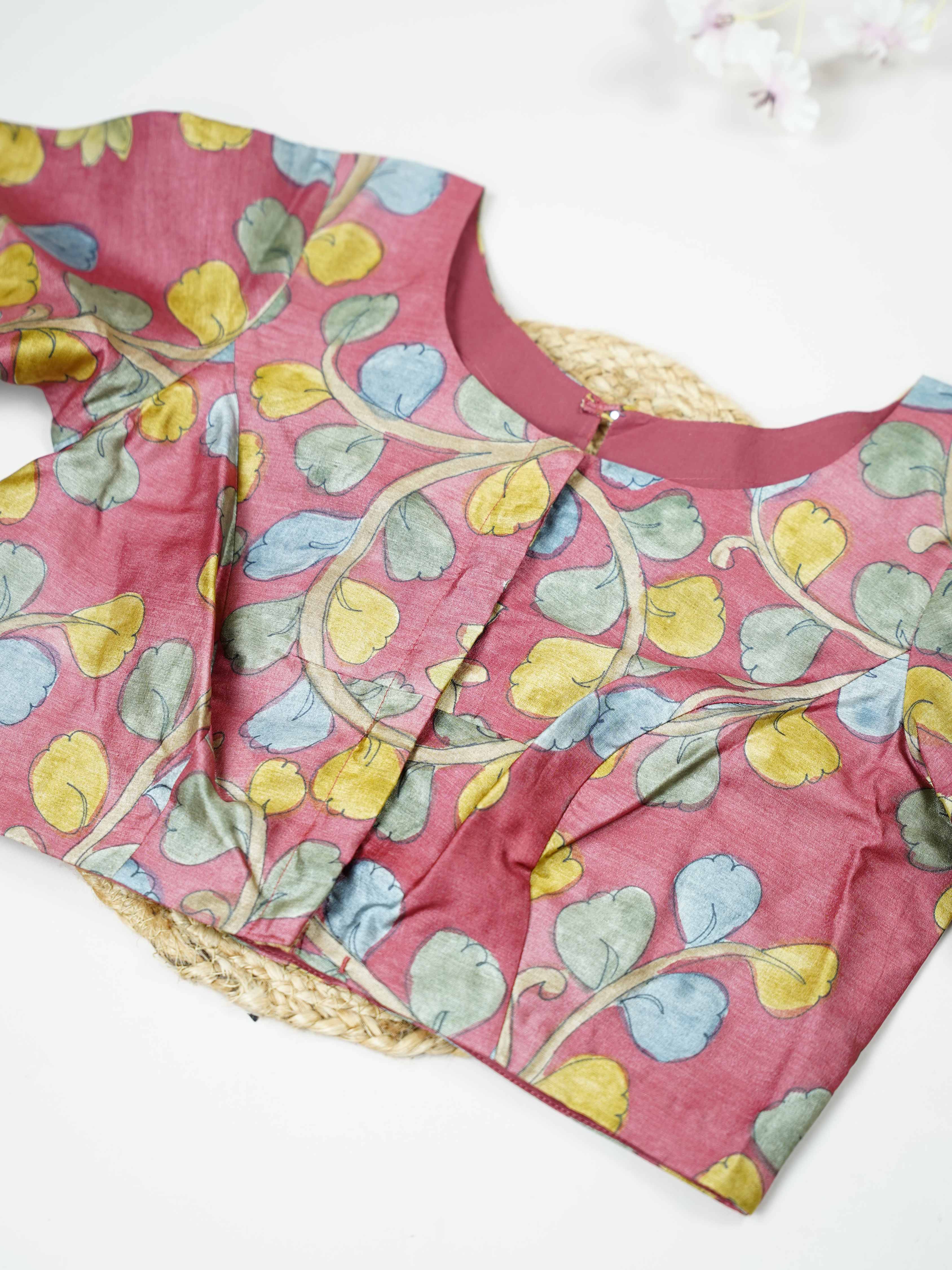 Tussar This elegant pink Tussar blouse features finely stitched hand-painted Pen Kalamkari floral designs. The delicate artwork showcases traditional craftsmanship with graceful and artistic detailing. The soft pink shade enhances the hand-painted flowers, giving it a charming ethnic appeal. Perfect for pairing with sarees, it creates a stylish and beautifully handcrafted traditional look. Kusuma - Tussar Silk Saree | Hand Embroidered - Manoranjitham Weaves - Handloom Store