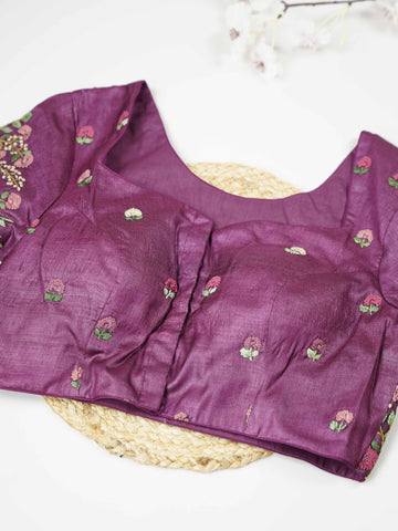 Tussar This elegant wine-coloured Tussar blouse features finely stitched hand embroidery work. The front is delicately designed with small floral motifs, adding a subtle feminine charm. Nyra - Tussar Silk Saree | Hand Embroidered - Manoranjitham Weaves - Handloom Store