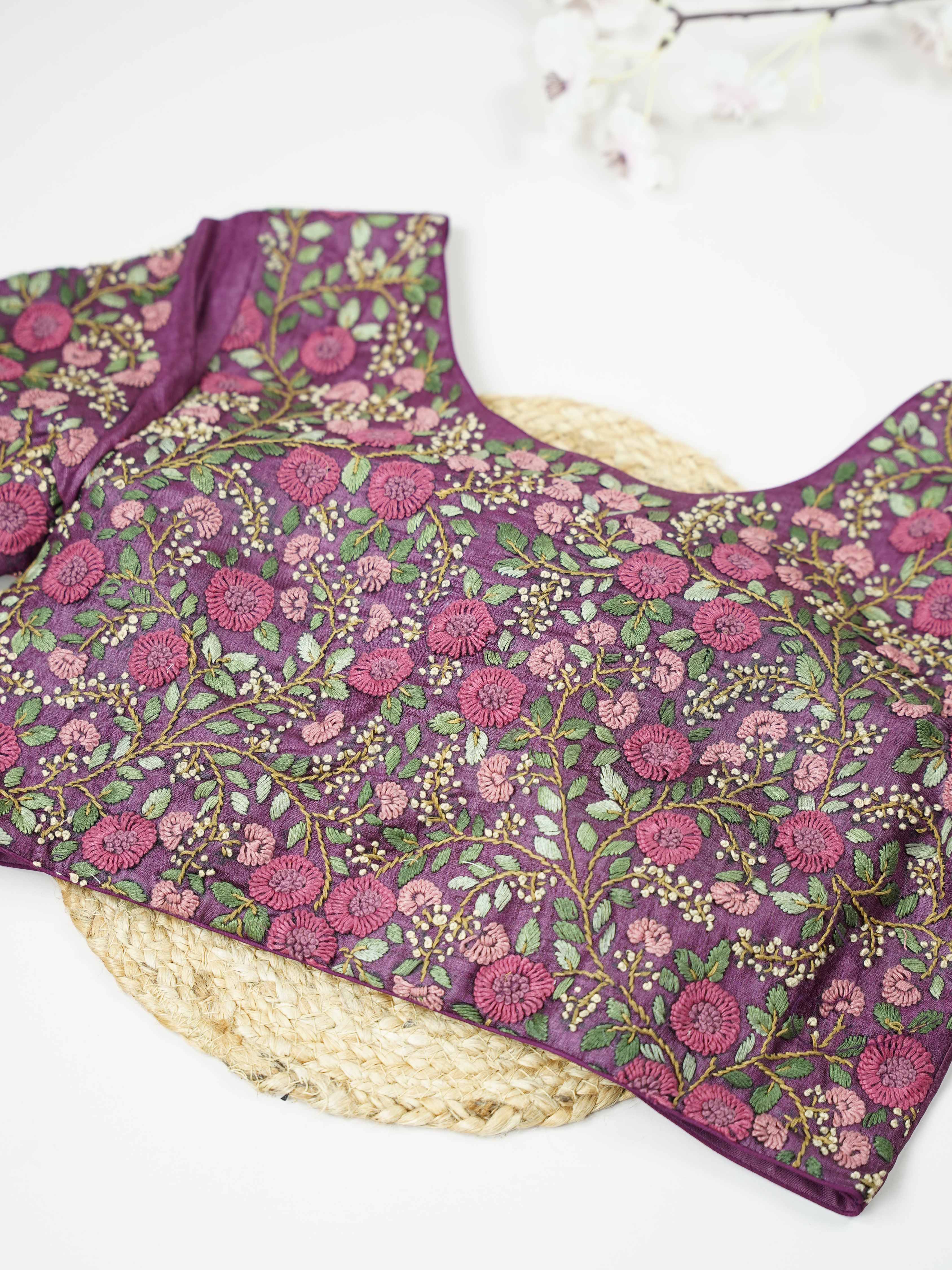 Tussar This elegant wine-coloured Tussar blouse features finely stitched hand embroidery work. The front is delicately designed with small floral motifs, adding a subtle feminine charm. Nyra - Tussar Silk Saree | Hand Embroidered - Manoranjitham Weaves - Handloom Store