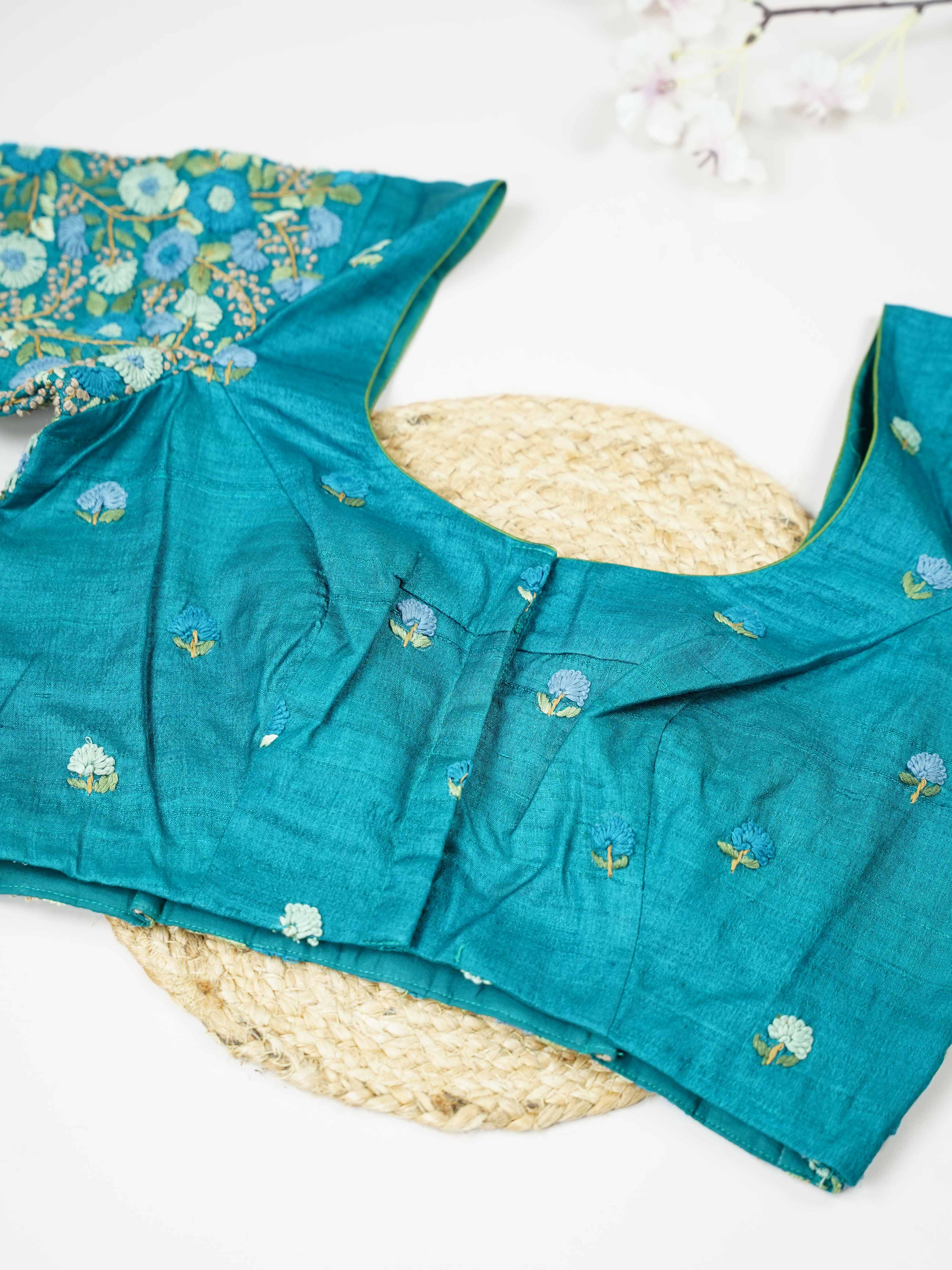 Tussar This elegant peacock blue Tussar designer blouse features finely stitched hand embroidery work. The front is adorned with small floral motifs, adding a delicate and graceful charm.br data-start=182 data-end=185The back is fully detailed with rich embroidery, showcasing intricate craftsmanship.br data-start=269 data-end=272Perfect for ethnic wear, it creates a bold, stylish, and beautifully balanced traditional look. Ira - Tussar Silk Saree | Hand Embroidered - Manoranjitham Weaves - Handloom Store