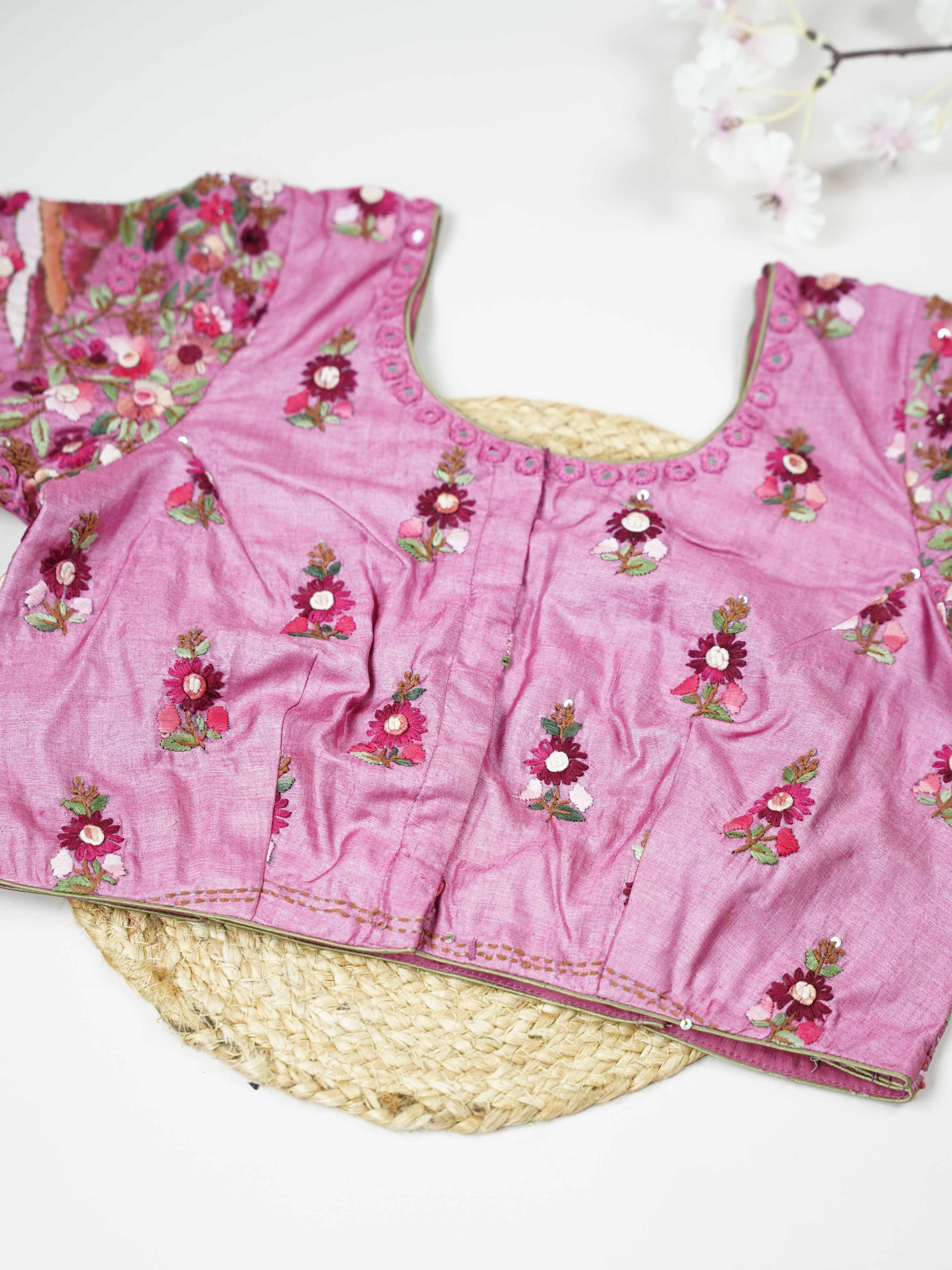 Tussar This elegant baby pink Tussar blouse features finely stitched hand embroidery work.br data-start=83 data-end=86The front is delicately designed with small floral motifs, adding a soft feminine charm.br data-start=174 data-end=177The back is richly adorned with full embroidery, showcasing detailed craftsmanship.br data-start=260 data-end=263Perfect for ethnic wear, it creates a graceful, stylish, and beautifully balanced traditional look. Iraya - Tussar Silk Saree | Hand Embroidered - Manoranjitham We
