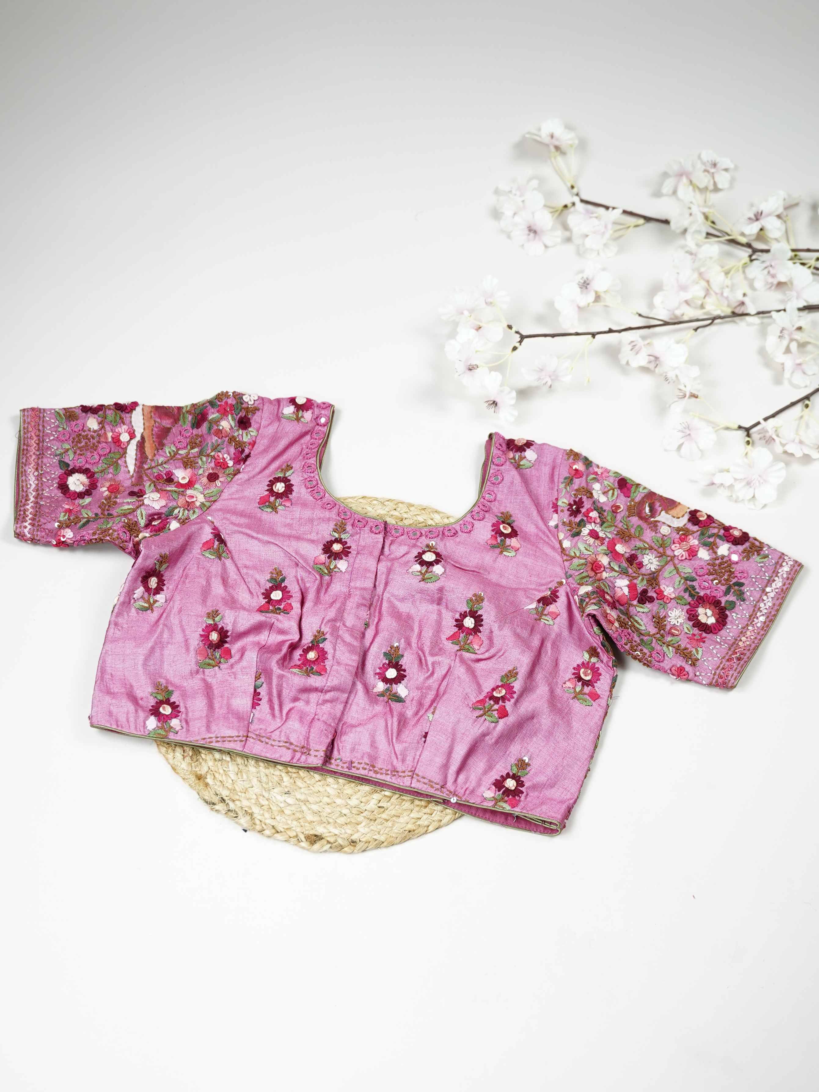 Tussar This elegant baby pink Tussar blouse features finely stitched hand embroidery work.br data-start=83 data-end=86The front is delicately designed with small floral motifs, adding a soft feminine charm.br data-start=174 data-end=177The back is richly adorned with full embroidery, showcasing detailed craftsmanship.br data-start=260 data-end=263Perfect for ethnic wear, it creates a graceful, stylish, and beautifully balanced traditional look. Iraya - Tussar Silk Saree | Hand Embroidered - Manoranjitham We