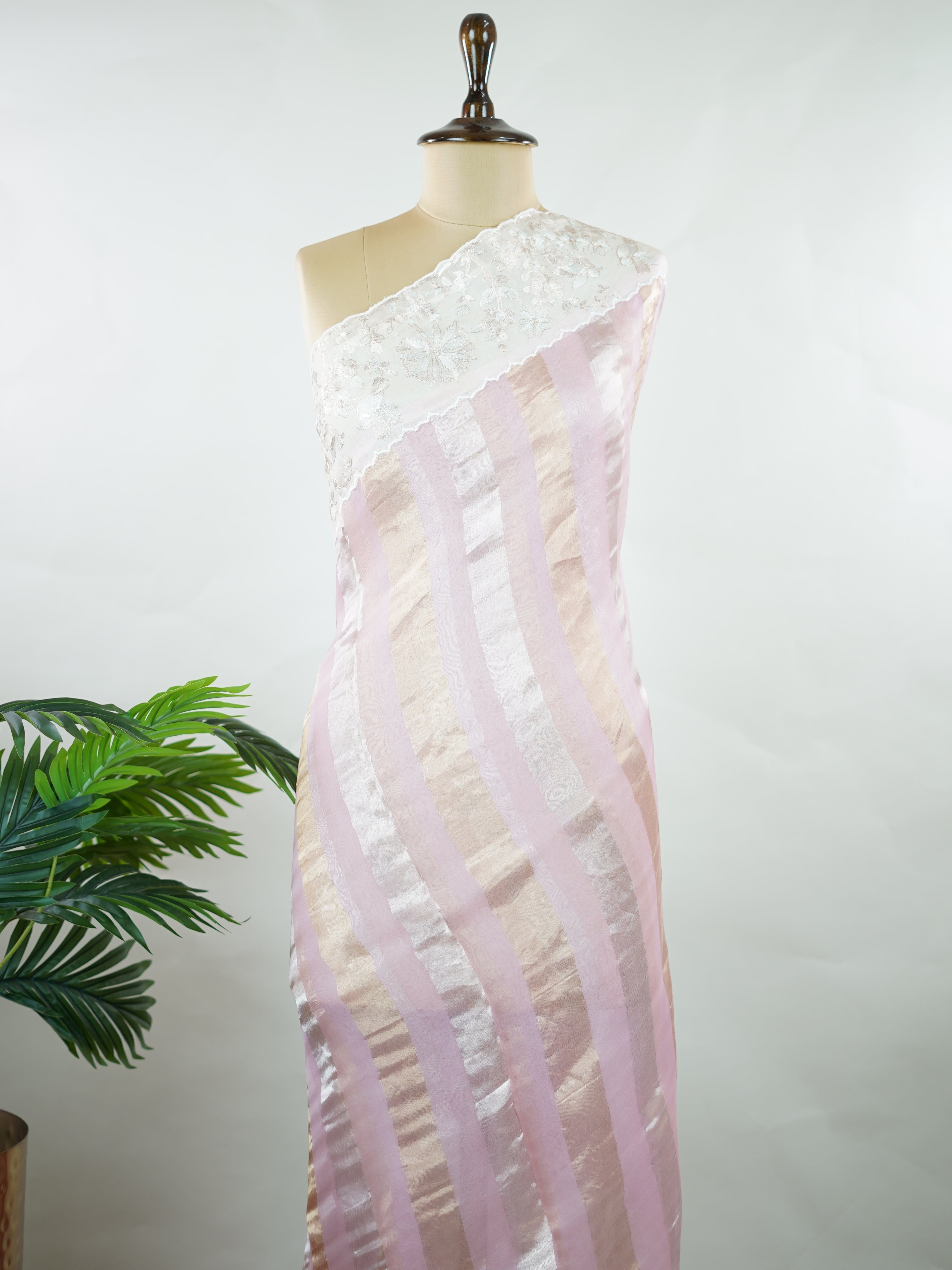 Organza Elegant organza saree in pink and white tones featuring delicate Aari Peeta work on the pallu. The sheer, lightweight fabric drapes softly, giving a graceful and feminine silhouette.br data-start=184 data-end=187Intricate handcrafted embroidery enhances its charm with rich detail and subtle elegance.br data-start=276 data-end=279Perfect for weddings, festive celebrations, and special occasions with timeless ethnic beauty. Aira - Organza Saree | Embroidered - Manoranjitham Weaves - Handloom Store