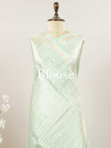 Tissue Step into subtle elegance with this tissue saree in a soothing powder green shade, paired with a matching blouse. The lightweight tissue fabric offers a soft, graceful shimmer that enhances its refined appeal. Delicate gold and silver buttas are woven throughout, adding a hint of festive charm and sophistication. Perfect for festive occasions, receptions, and elegant gatherings that call for understated beauty. Charukesi - Banarasi Tissue Kora Saree | Lightweight | Woven Buttas - Manoranjitham Weaves