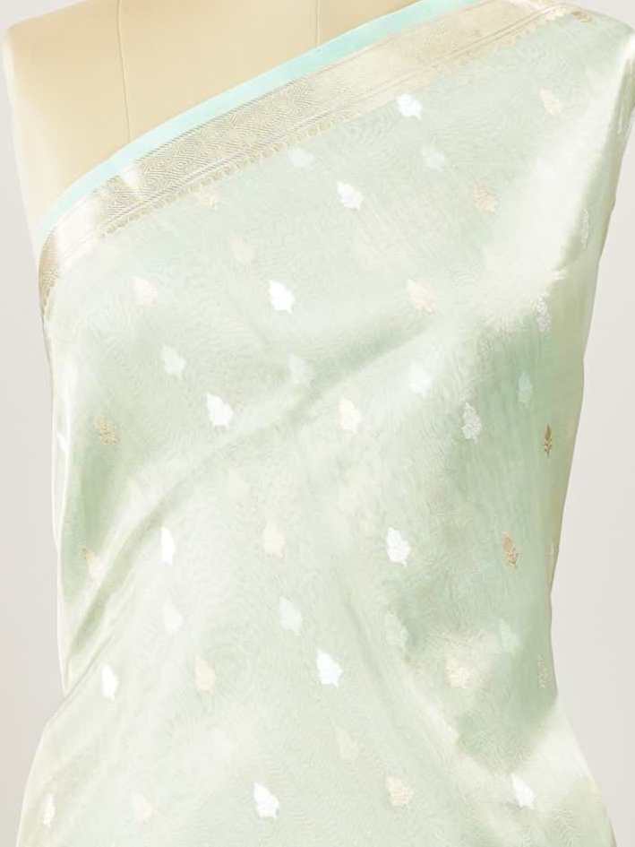 Tissue Step into subtle elegance with this tissue saree in a soothing powder green shade, paired with a matching blouse. The lightweight tissue fabric offers a soft, graceful shimmer that enhances its refined appeal. Delicate gold and silver buttas are woven throughout, adding a hint of festive charm and sophistication. Perfect for festive occasions, receptions, and elegant gatherings that call for understated beauty. Charukesi - Banarasi Tissue Kora Saree | Lightweight | Woven Buttas - Manoranjitham Weaves