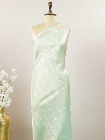 Tissue Step into subtle elegance with this tissue saree in a soothing powder green shade, paired with a matching blouse. The lightweight tissue fabric offers a soft, graceful shimmer that enhances its refined appeal. Delicate gold and silver buttas are woven throughout, adding a hint of festive charm and sophistication. Perfect for festive occasions, receptions, and elegant gatherings that call for understated beauty. Charukesi - Banarasi Tissue Kora Saree | Lightweight | Woven Buttas - Manoranjitham Weaves