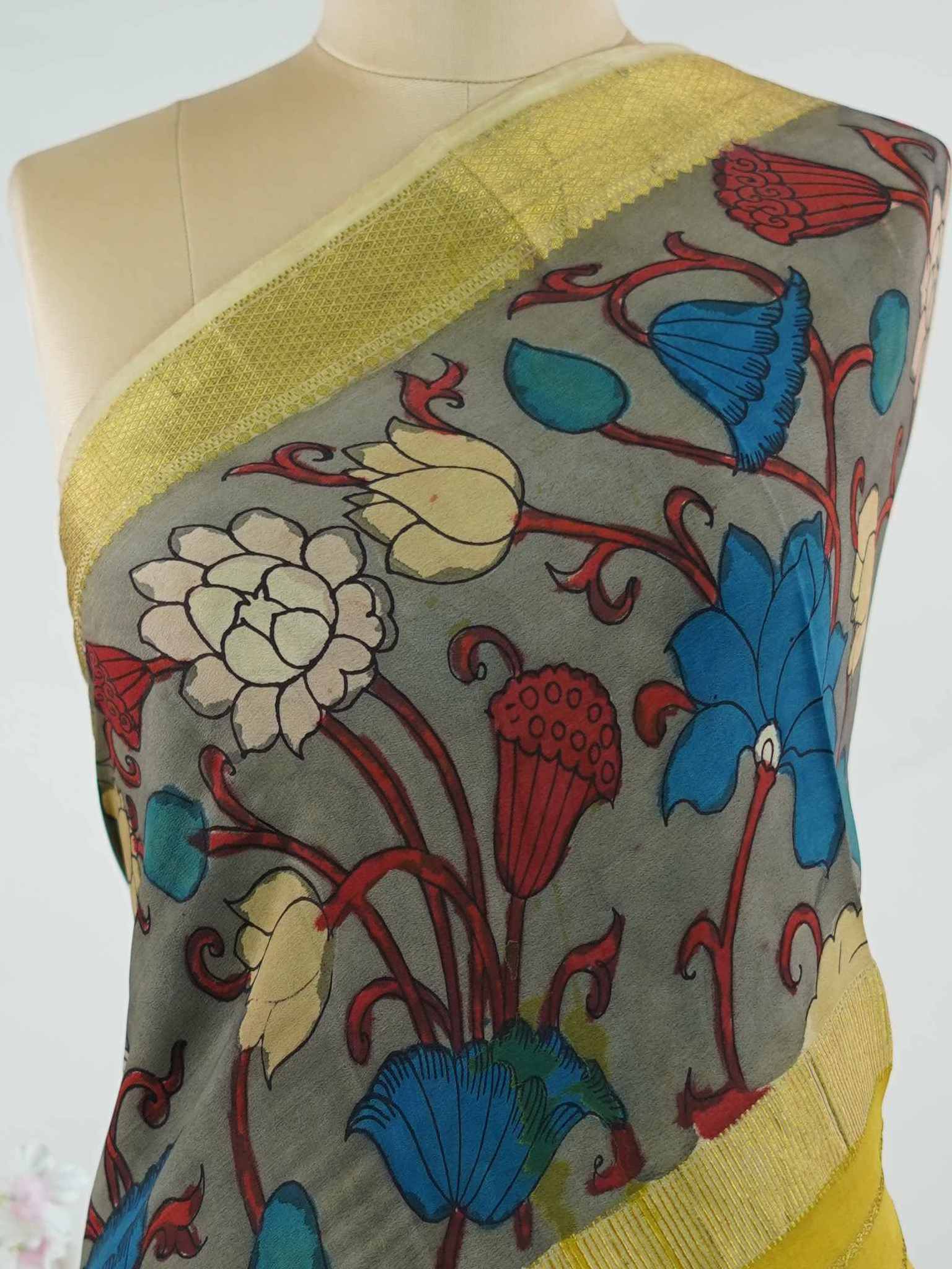 Mysore silk This Mysore silk saree is a quiet celebration of two worlds beautifully united — one half draped in the cool, understated elegance of pure grey silk, the other brought alive with intricate pen Kalamkari artistry in earthy, hand-drawn motifs. The 100% pure silk body carries that characteristic Mysore sheen, smooth and weightless against the skin, while the Kalamkari half tells a story in every careful line and curve. Zari accents frame the drape with a subtle gleam, never overpowering the artistr