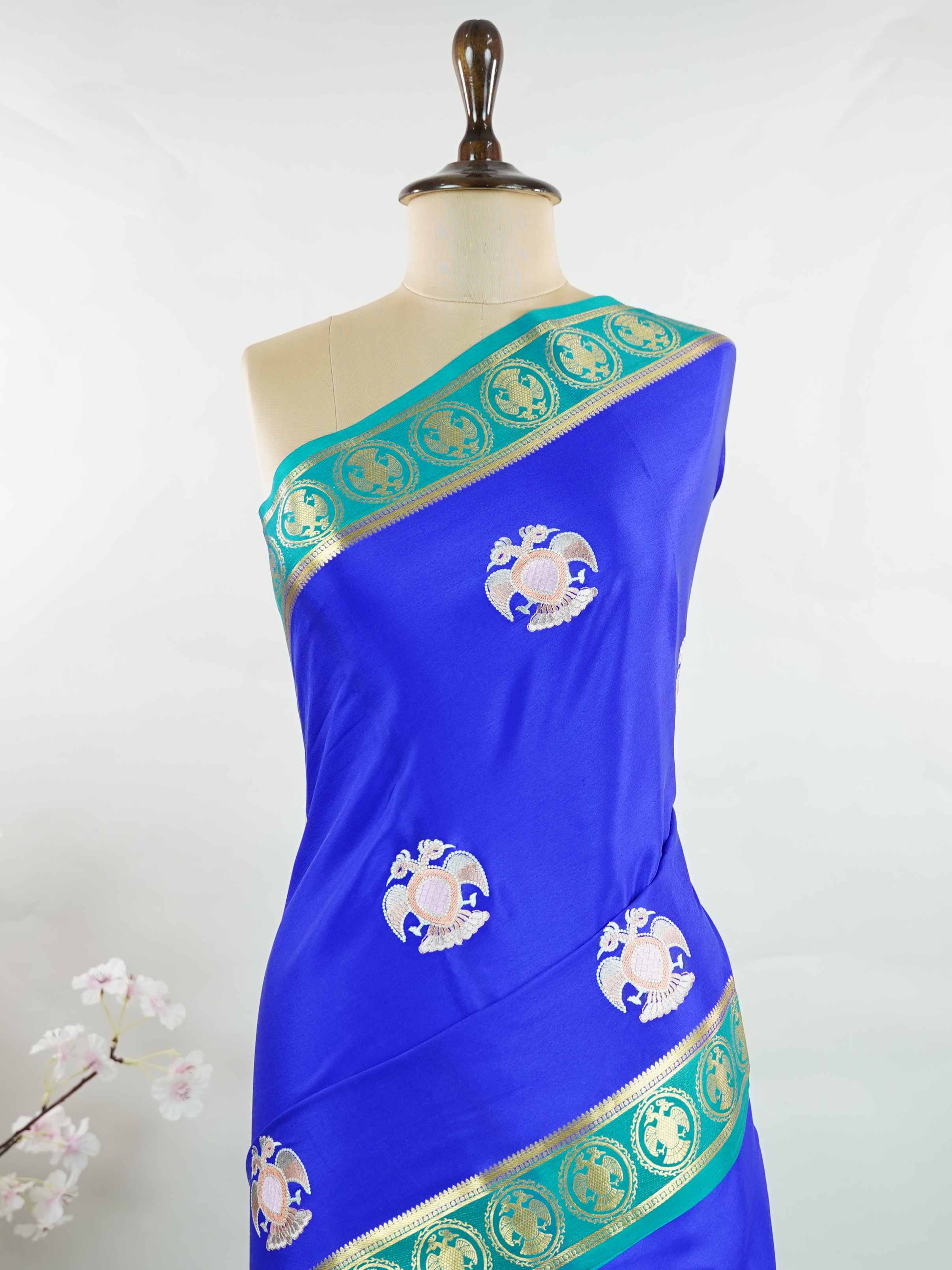 Mysore silk Rich blue Mysore silk featuring traditional checks and intricately woven Gandaberunda motifs across the body. A graceful Mysore silk saree crafted using pure handloom techniques. Its soft silk weave offers elegance with comfort. Simple styling adds timeless sophistication. Woven to reflect heritage and artistry. A beautiful saree for every occasion.brA graceful blend of heritage craftsmanship and timeless South Indian elegance. Tejomayi - Blue Pure Mysore Silk Saree | Gandaberunda Motifs - Manor