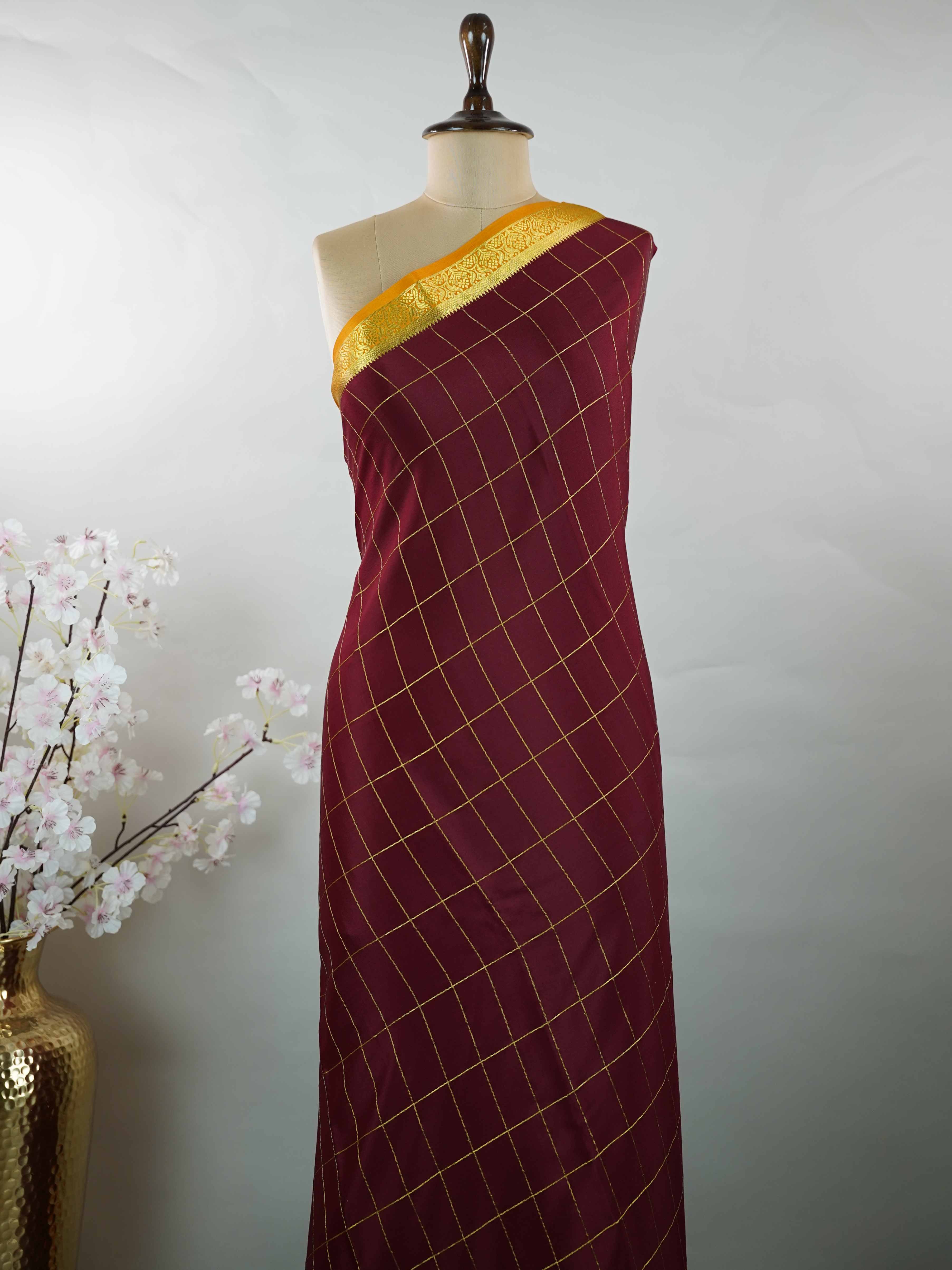 Mysore silk Pure Mysore silk in a rich maroon hue, complemented by classic checks woven gracefully across the body.br
Paired with a vibrant mustard yellow contrast, this weave exudes timeless charm and quiet sophistication. Vilasini - Maroon Pure Mysore Silk Saree | Classic Checks - Manoranjitham Weaves - Handloom Store
